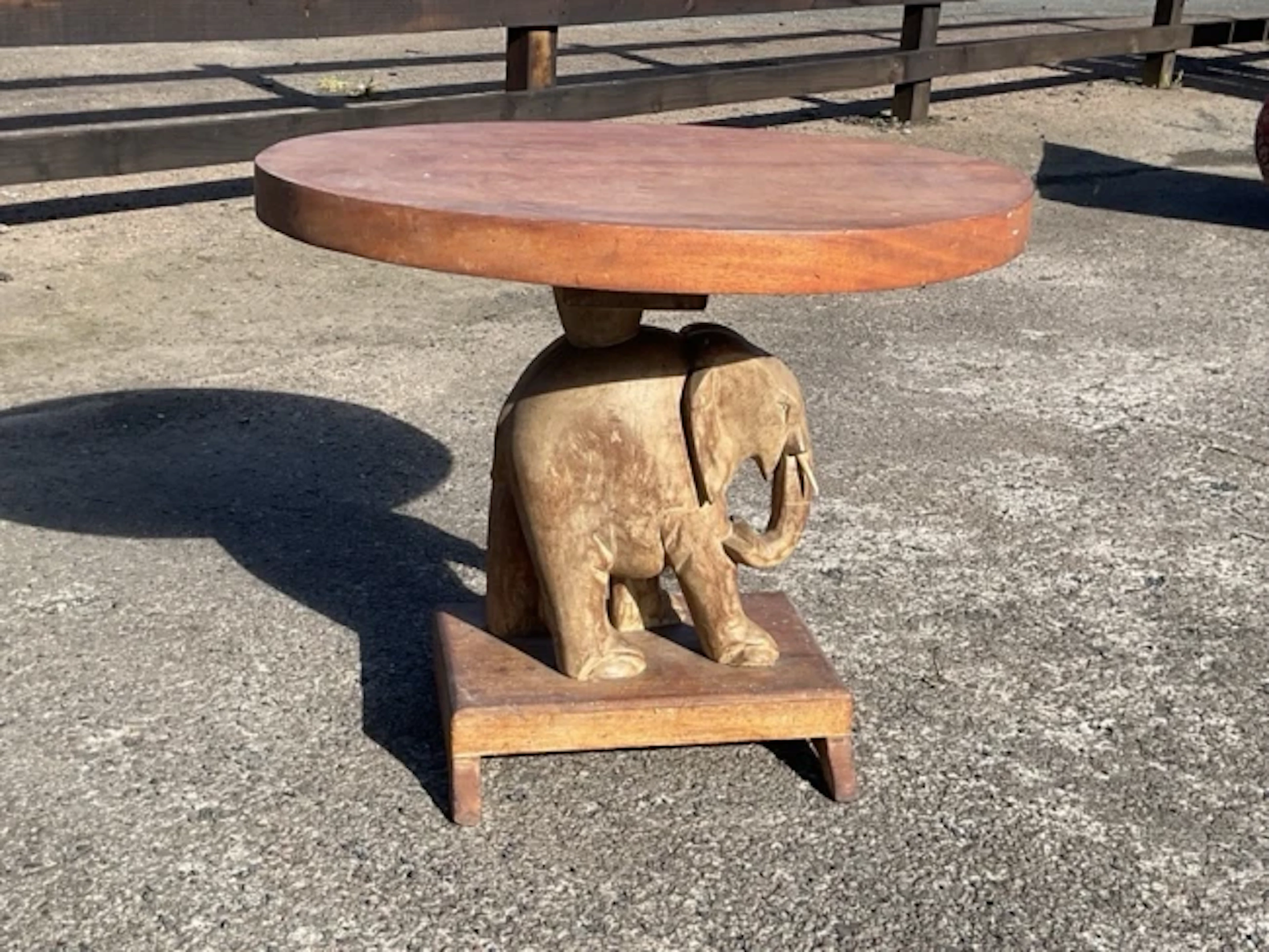 A mahogany coffee table, the thick circular top supported by a carved