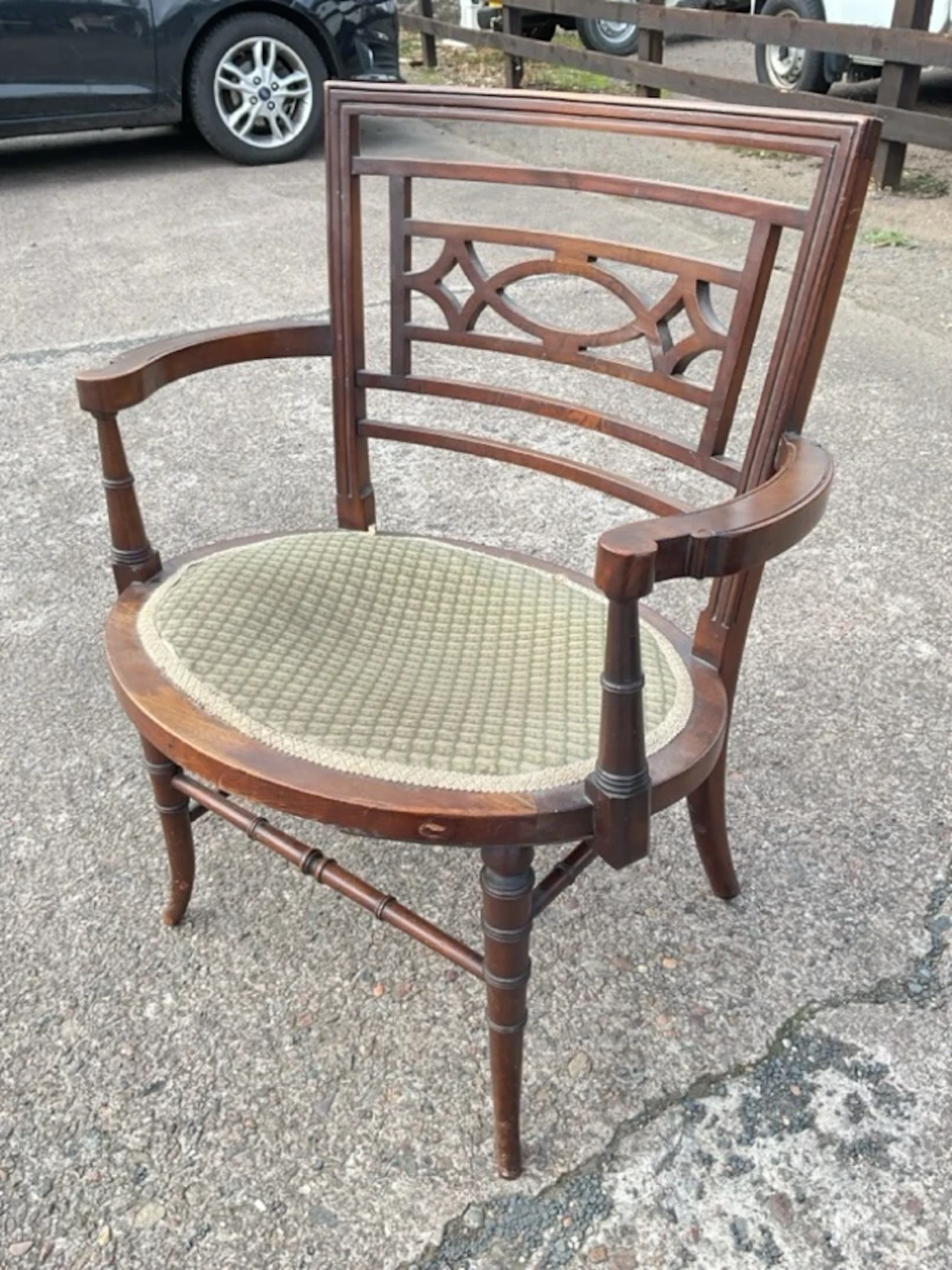 An oval Edwardian mahogany armchair with fretwork back and rounded