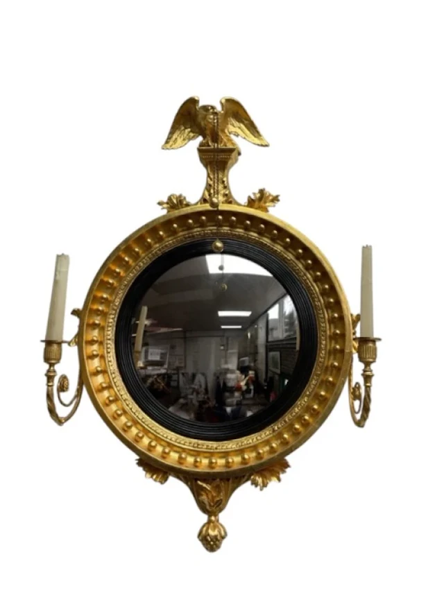 A regency carved gilt pine convex girandole mirror with eagle finial