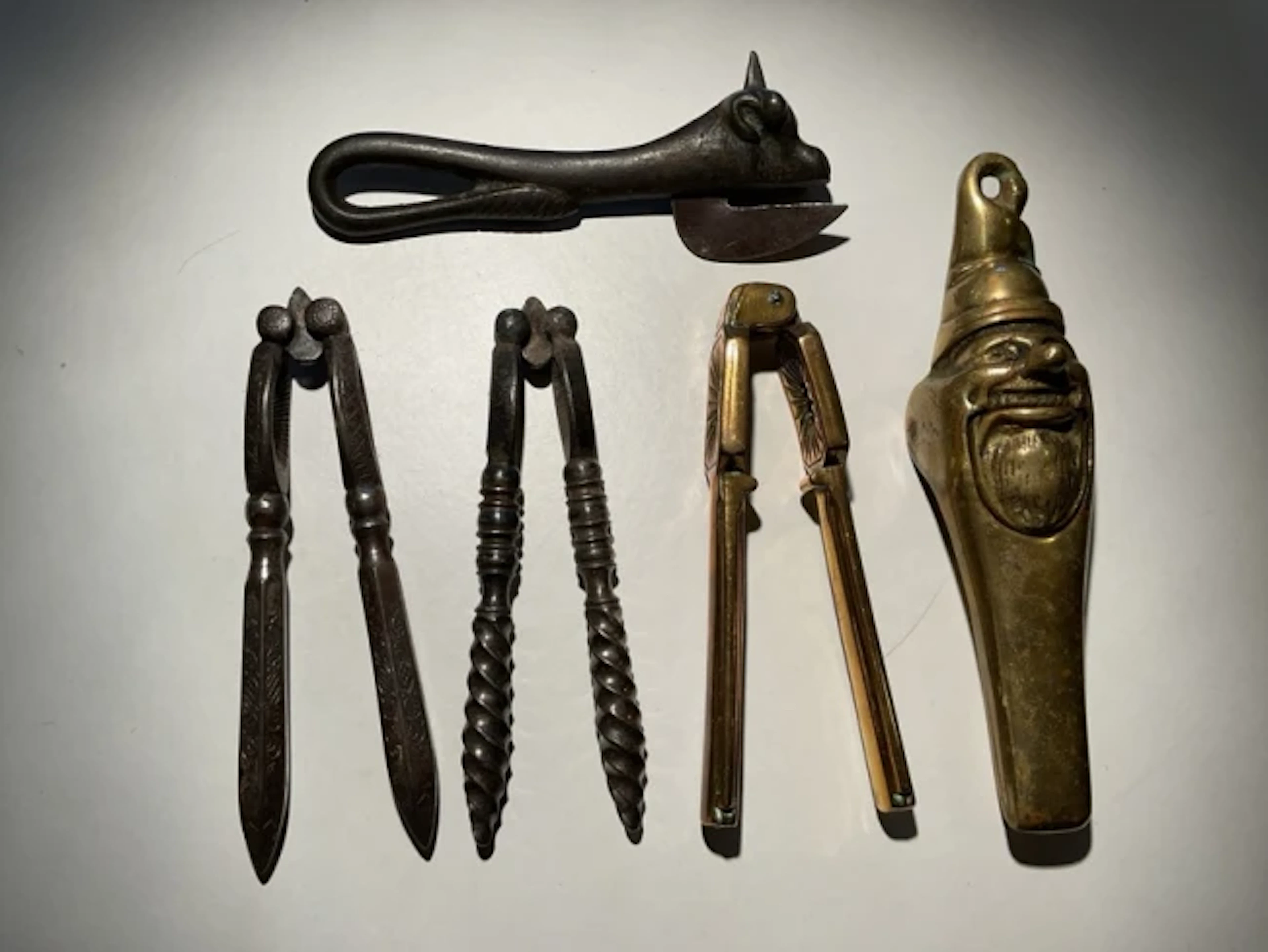 Four old nutcrackers - brass gnome type, twisted handled, scroll engraved