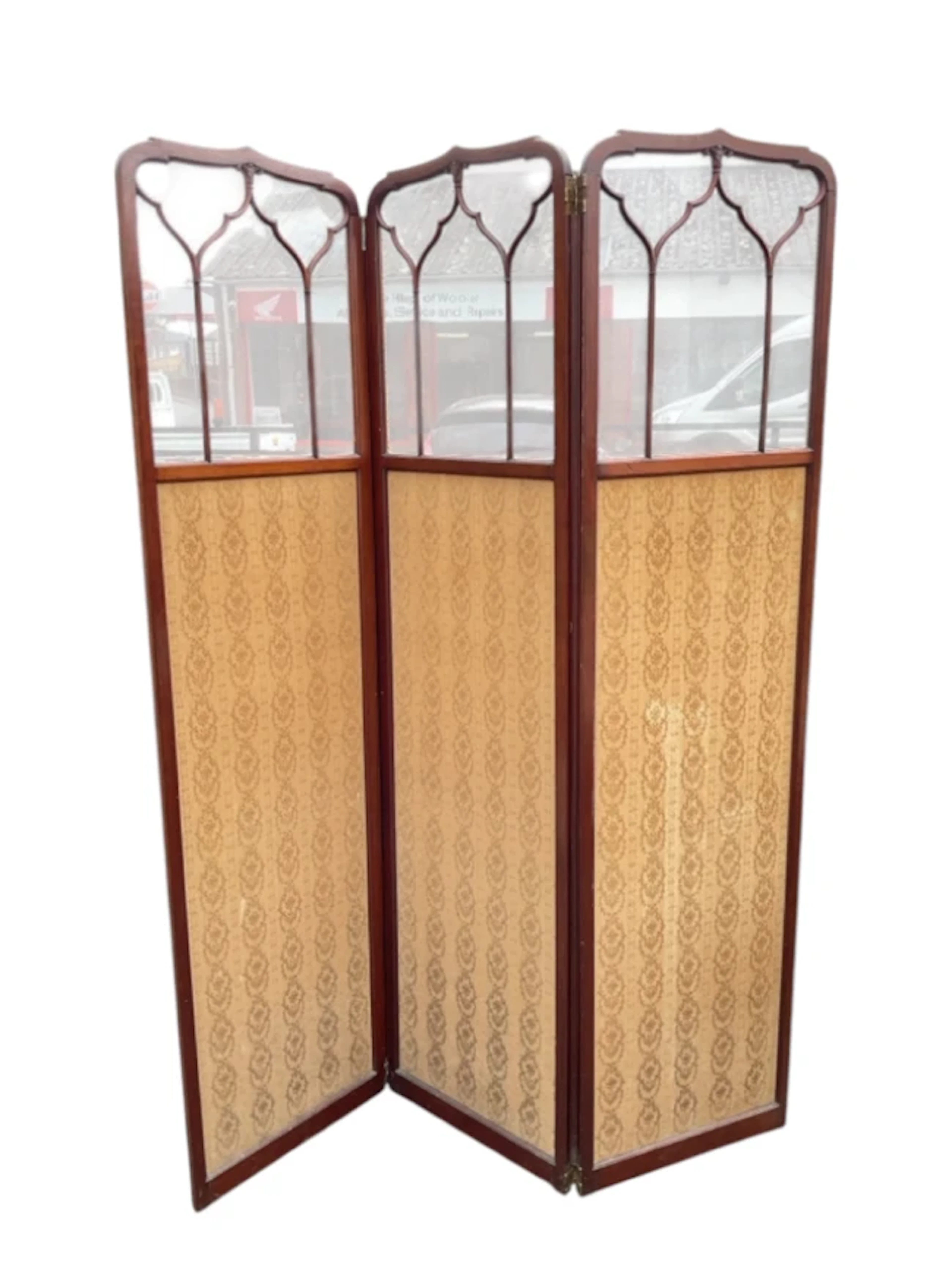 An Edwardian three-fold mahogany screen with glazed gothic arched