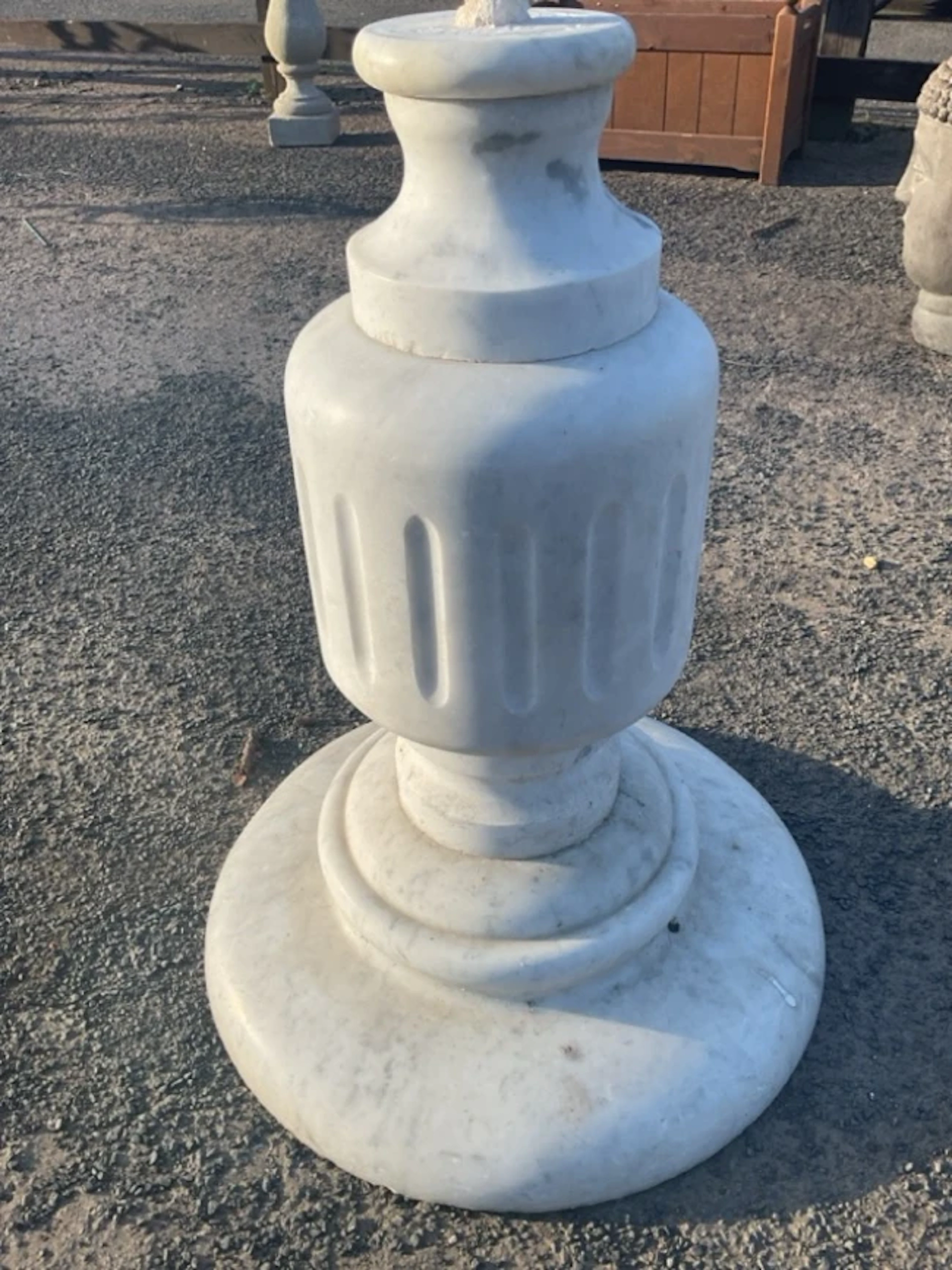 A white marble stand of capstan form with fluted drum to column, on