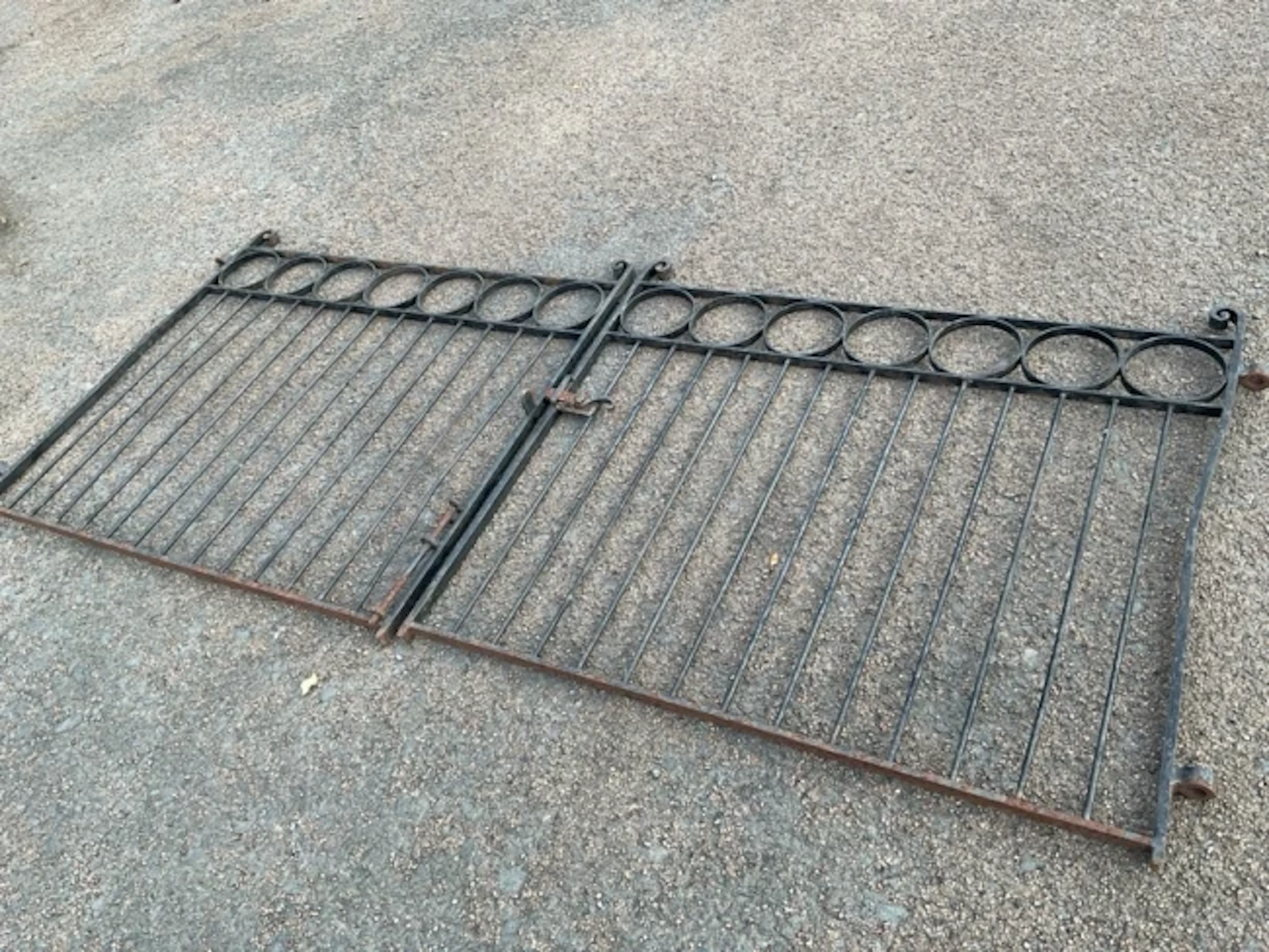 A pair of wrought iron driveway gates with scrolled finials to cornerposts