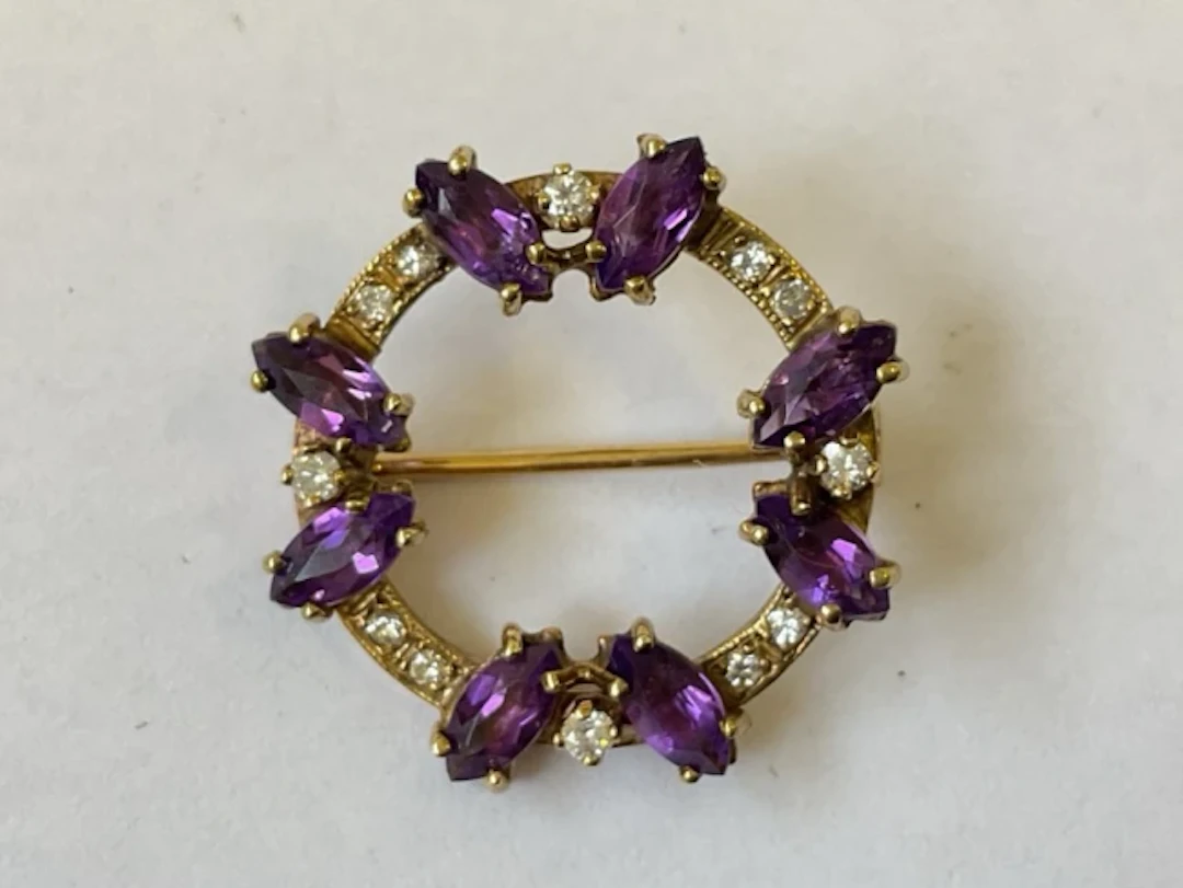 A 9ct gold brooch set with four pairs of marquise cut amethysts at