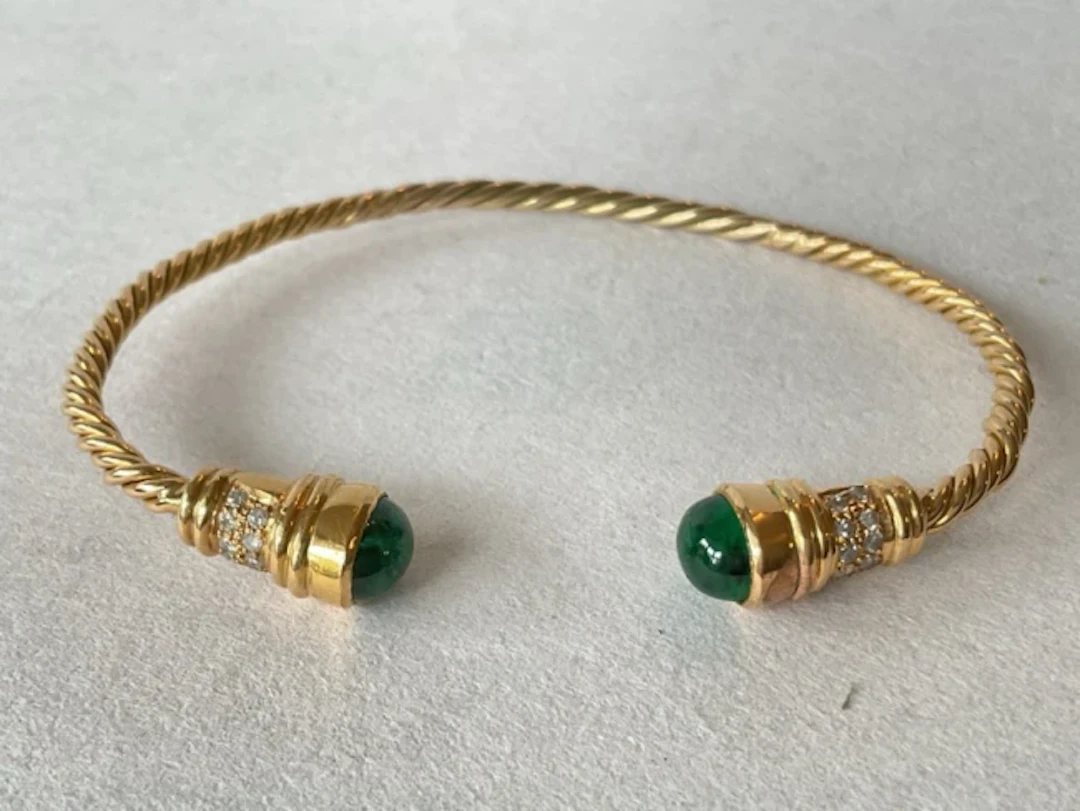 An 18ct gold rope-twist sprung bangle, the ends set with cabochon