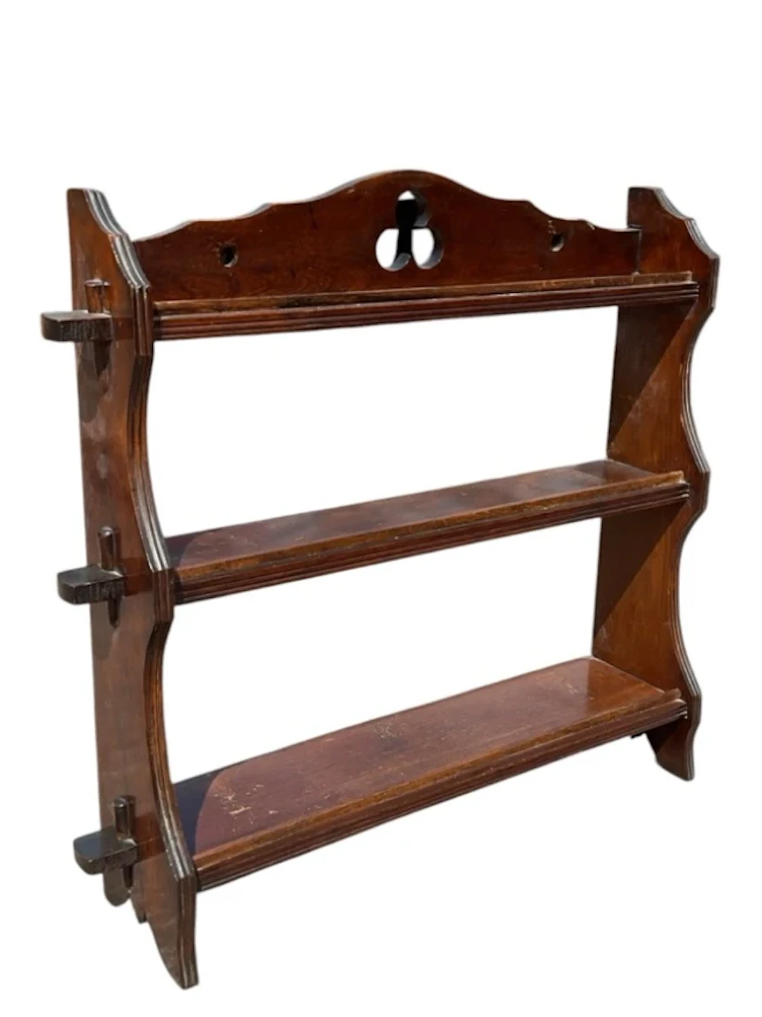 A stained pine plate rack with three pegged shelves on ribbed shaped