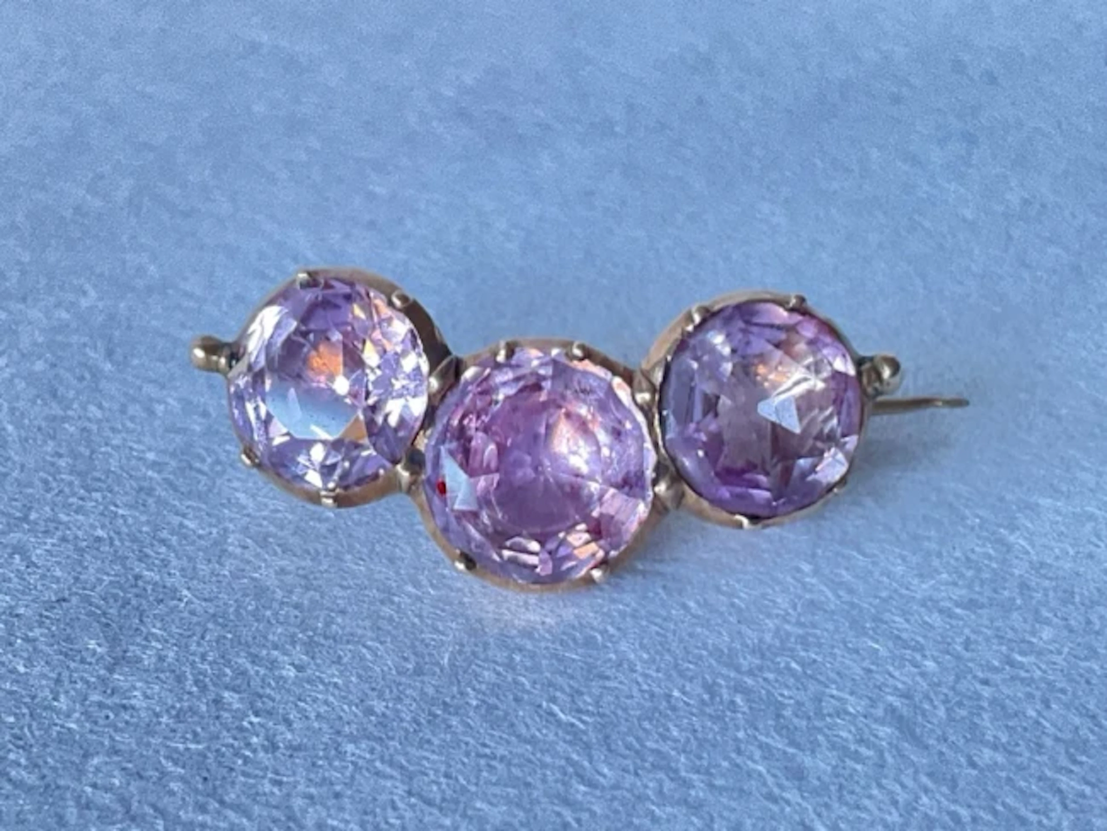 A Georgian gold brooch set with a trio of circular cut amethysts. (1in)