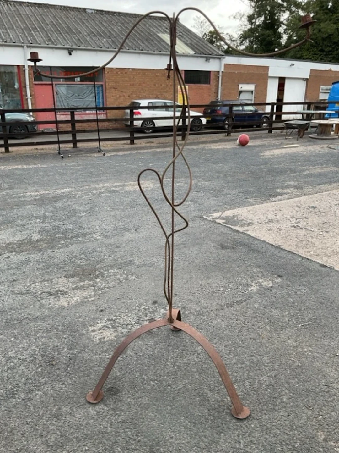 A rusty old wrought iron garden candelabra with wavy branches and