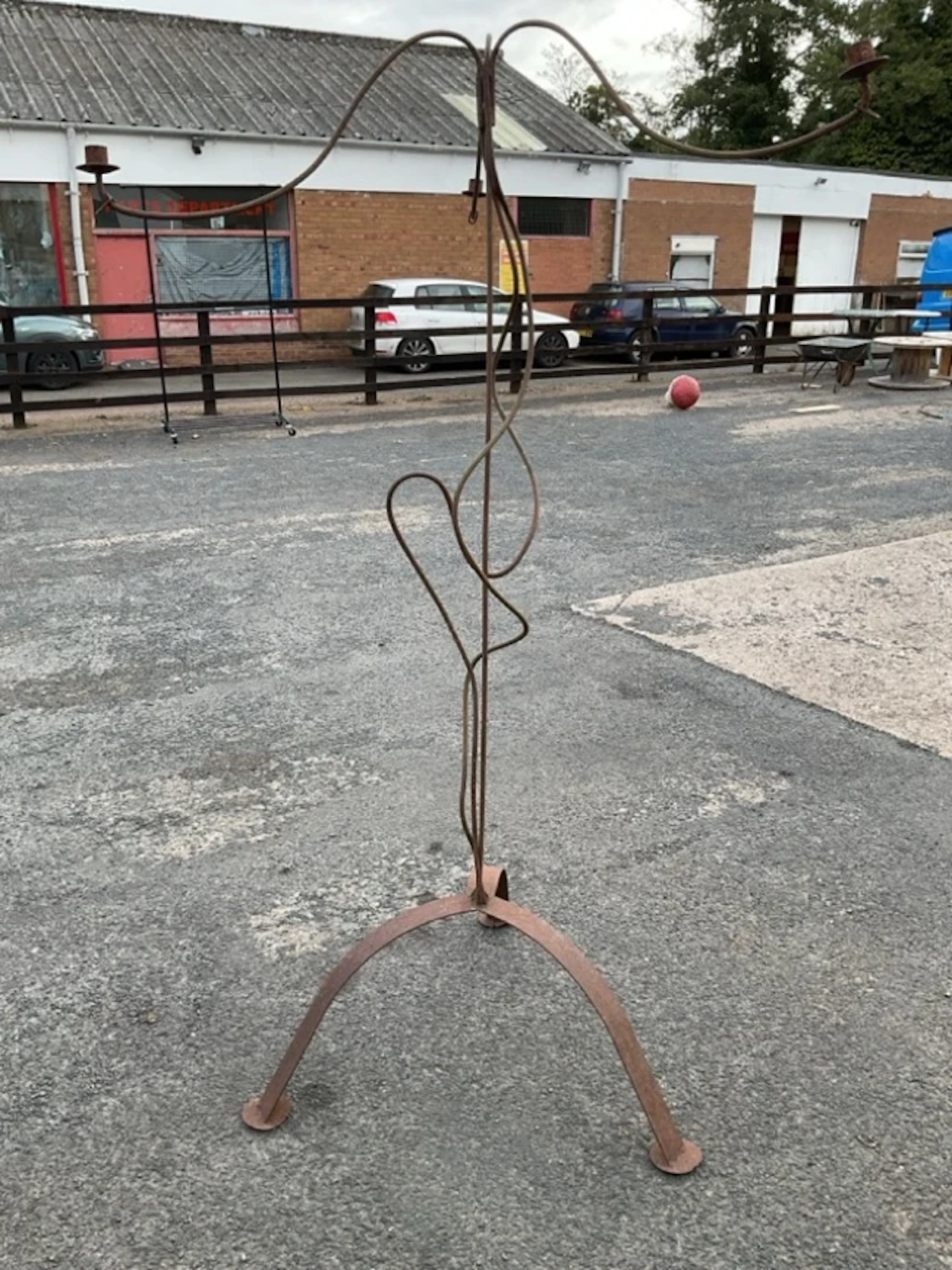 A rusty old wrought iron garden candelabra with wavy branches and