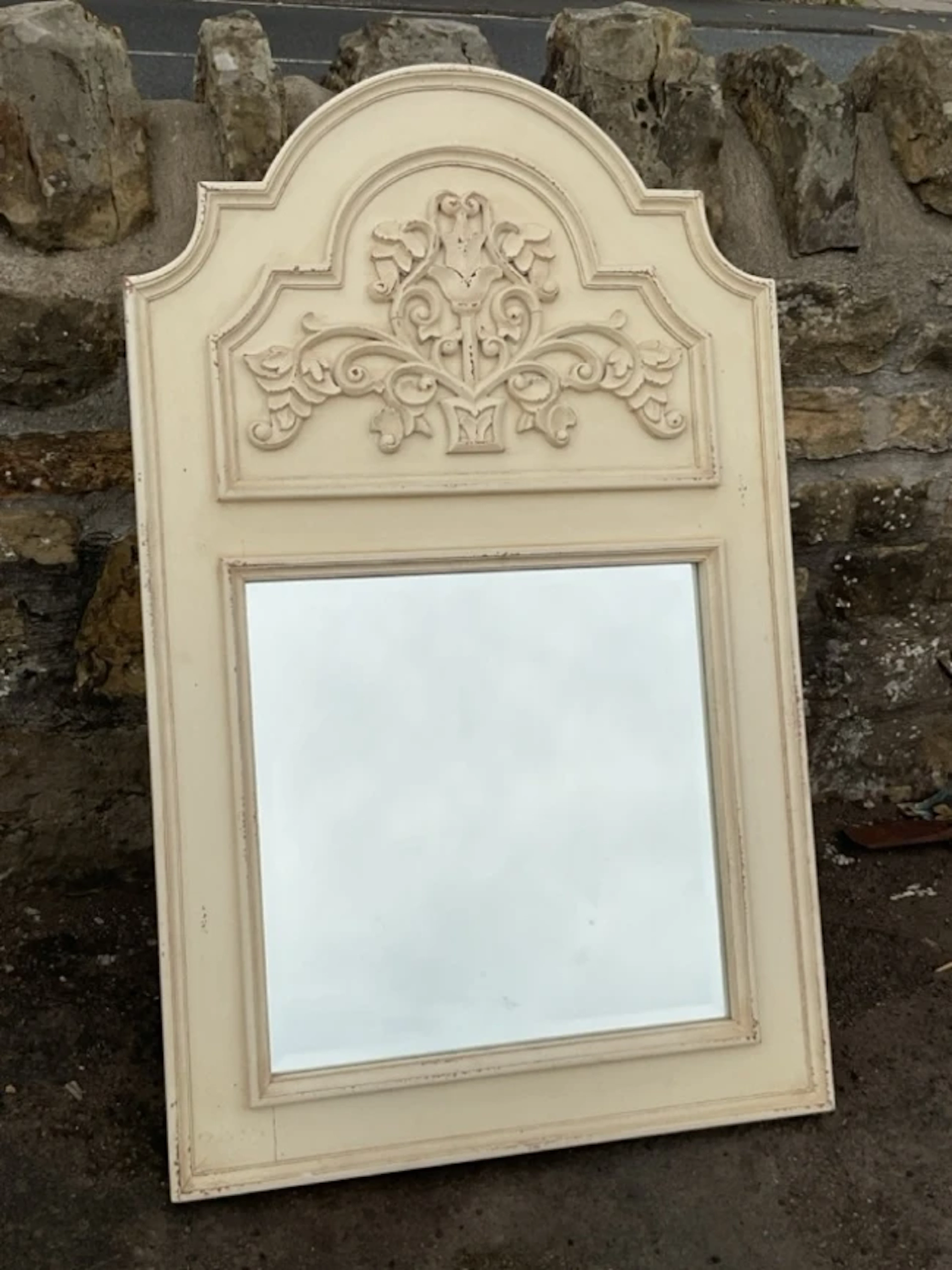 A hall mirror with arched frame around a panel with foliate scrolled