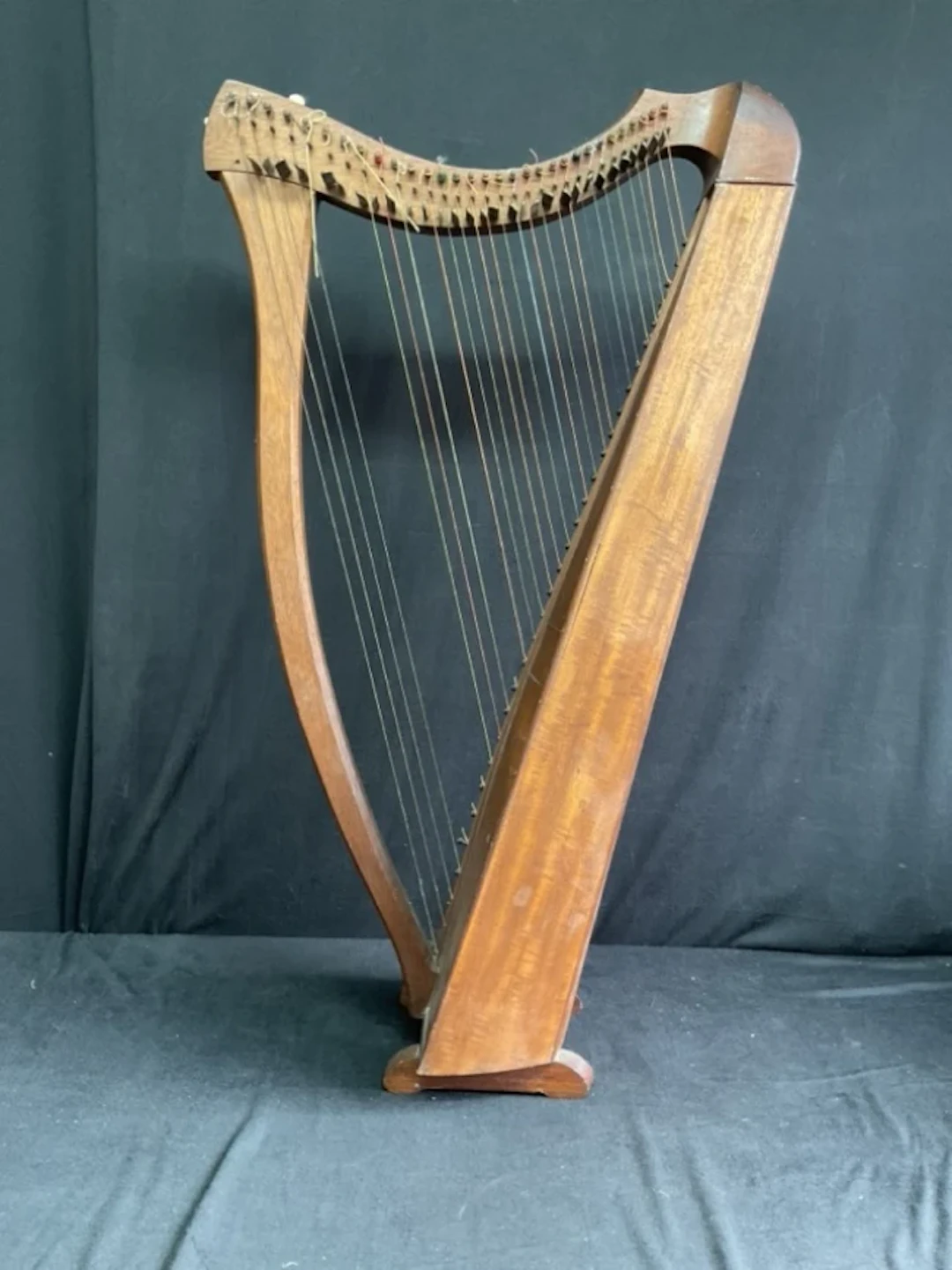 A mahogany Celtic harp with serpentine harmonic curve, T-brace and