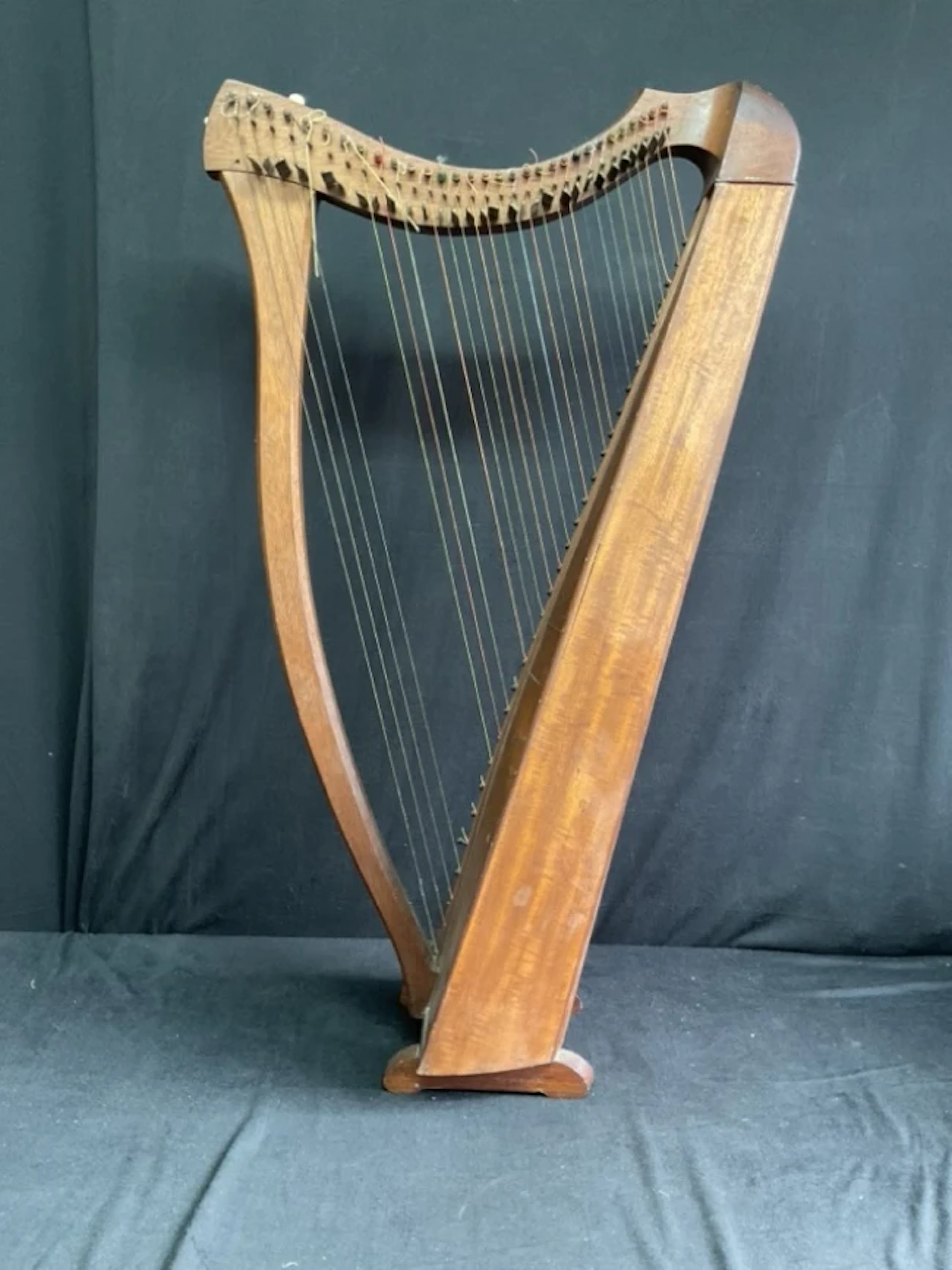 A mahogany Celtic harp with serpentine harmonic curve, T-brace and