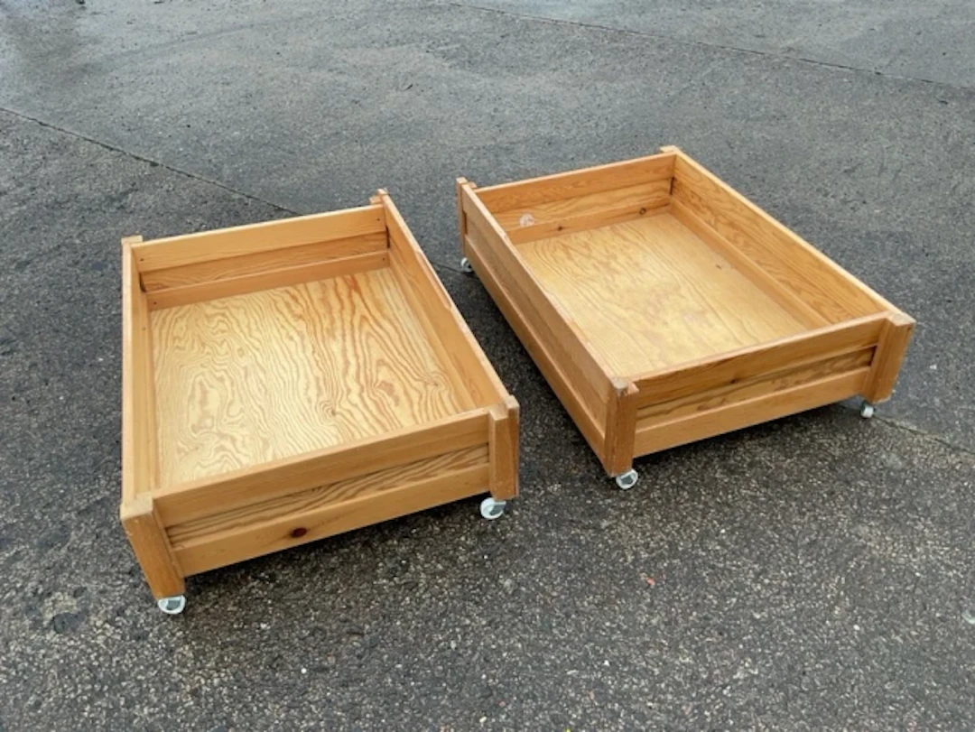 A pair of pine under-bed lockers, the panelled drawer type boxes on