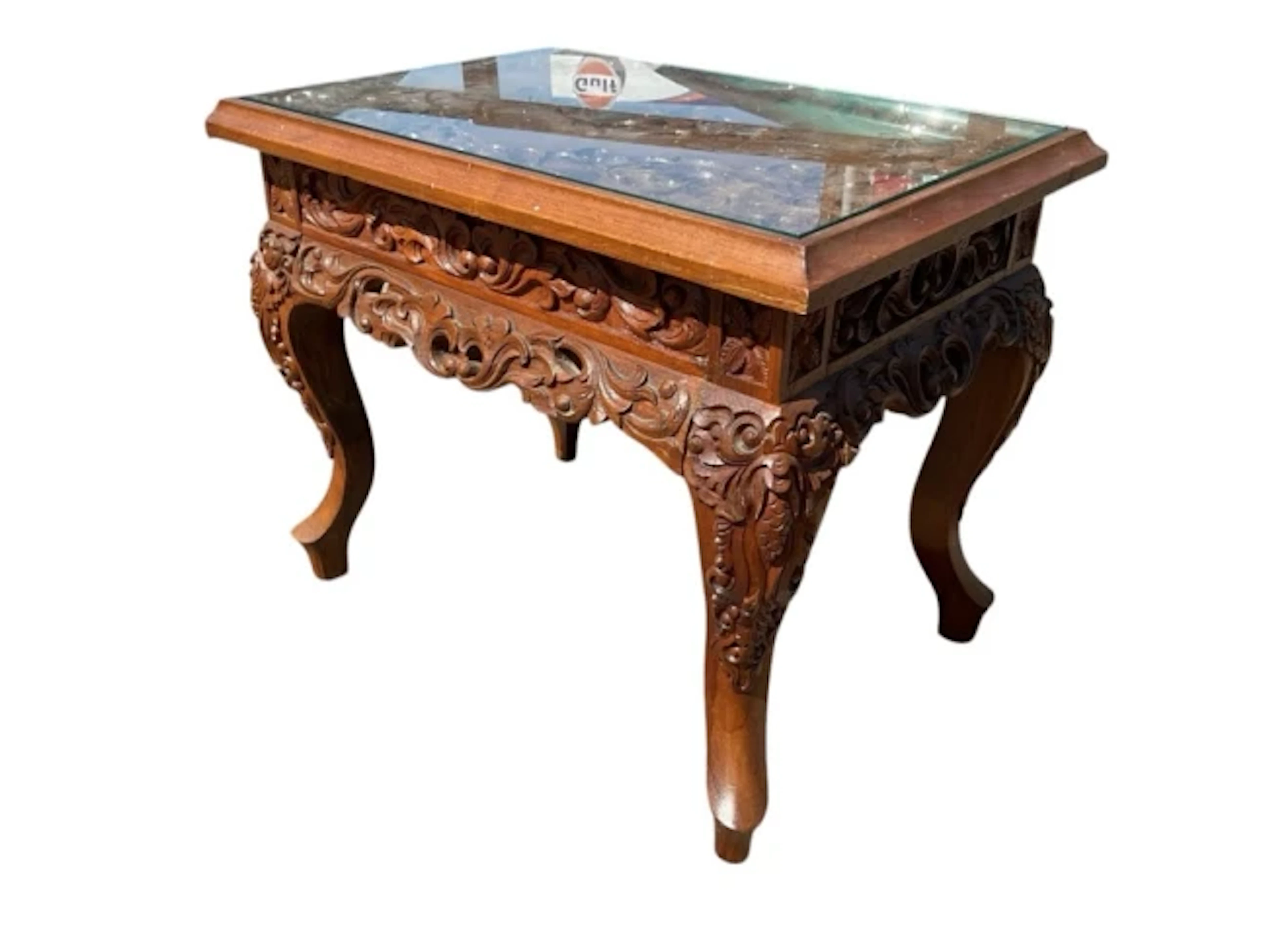 A carved mahogany coffee table with plate glass top above a foliate