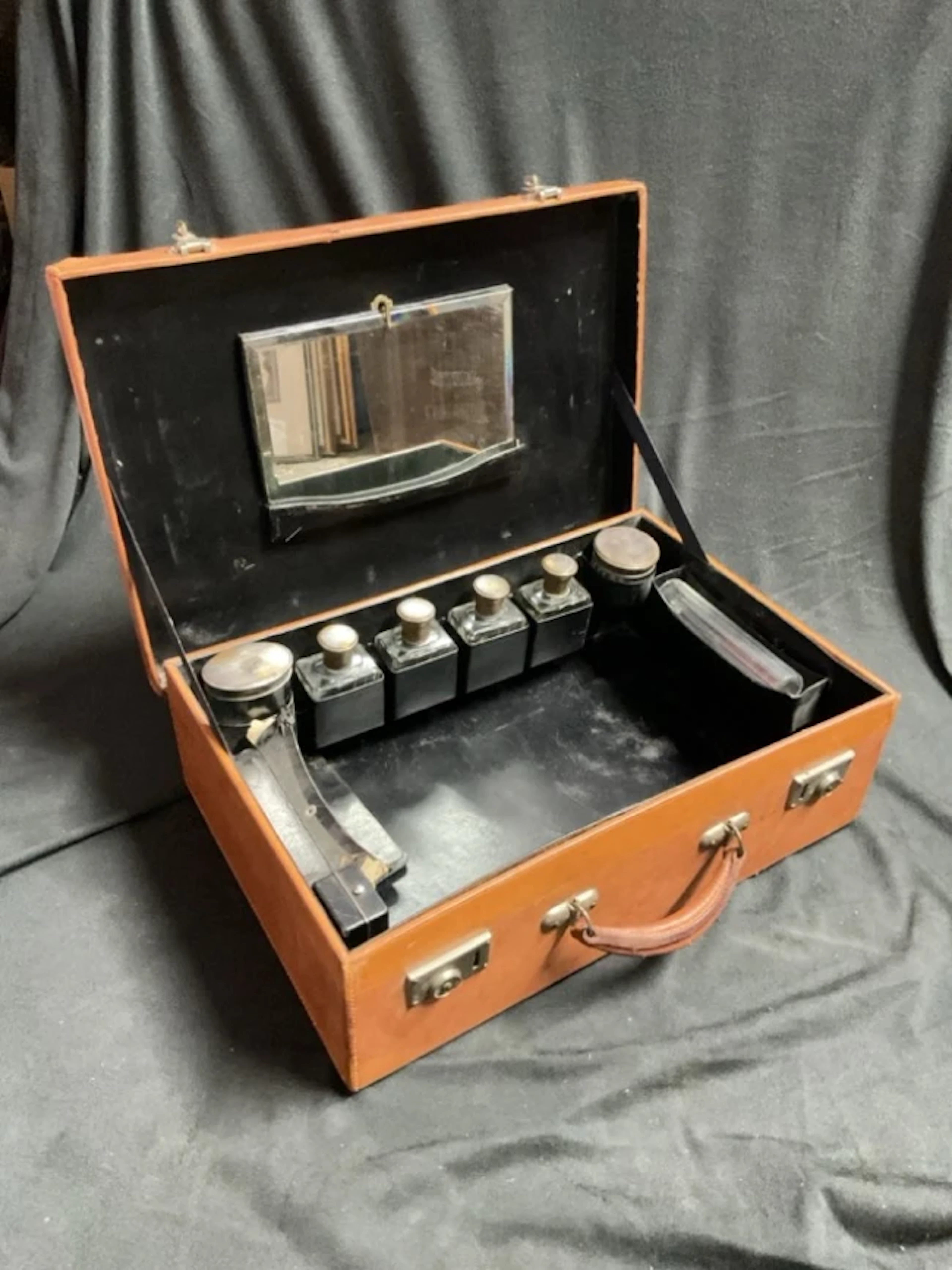 A 20s pigskin dressing case with nickel locks opening to a fitted