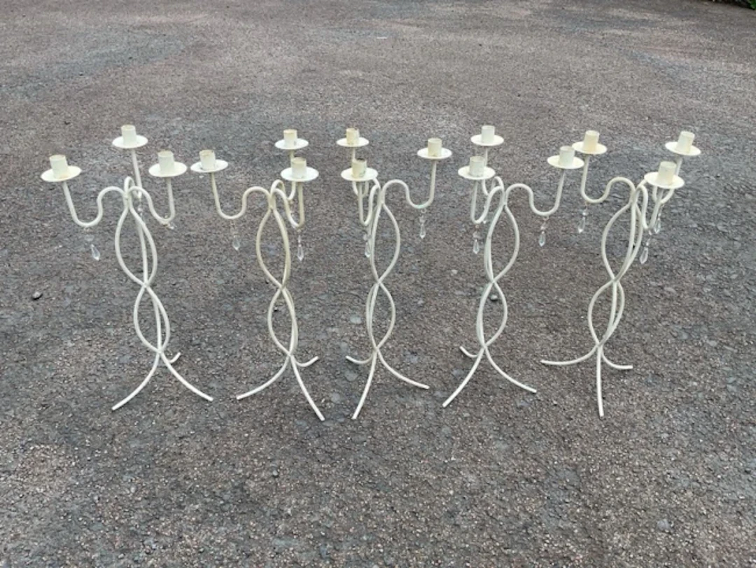 A set of five painted wrought iron candelabra each with three candleholders