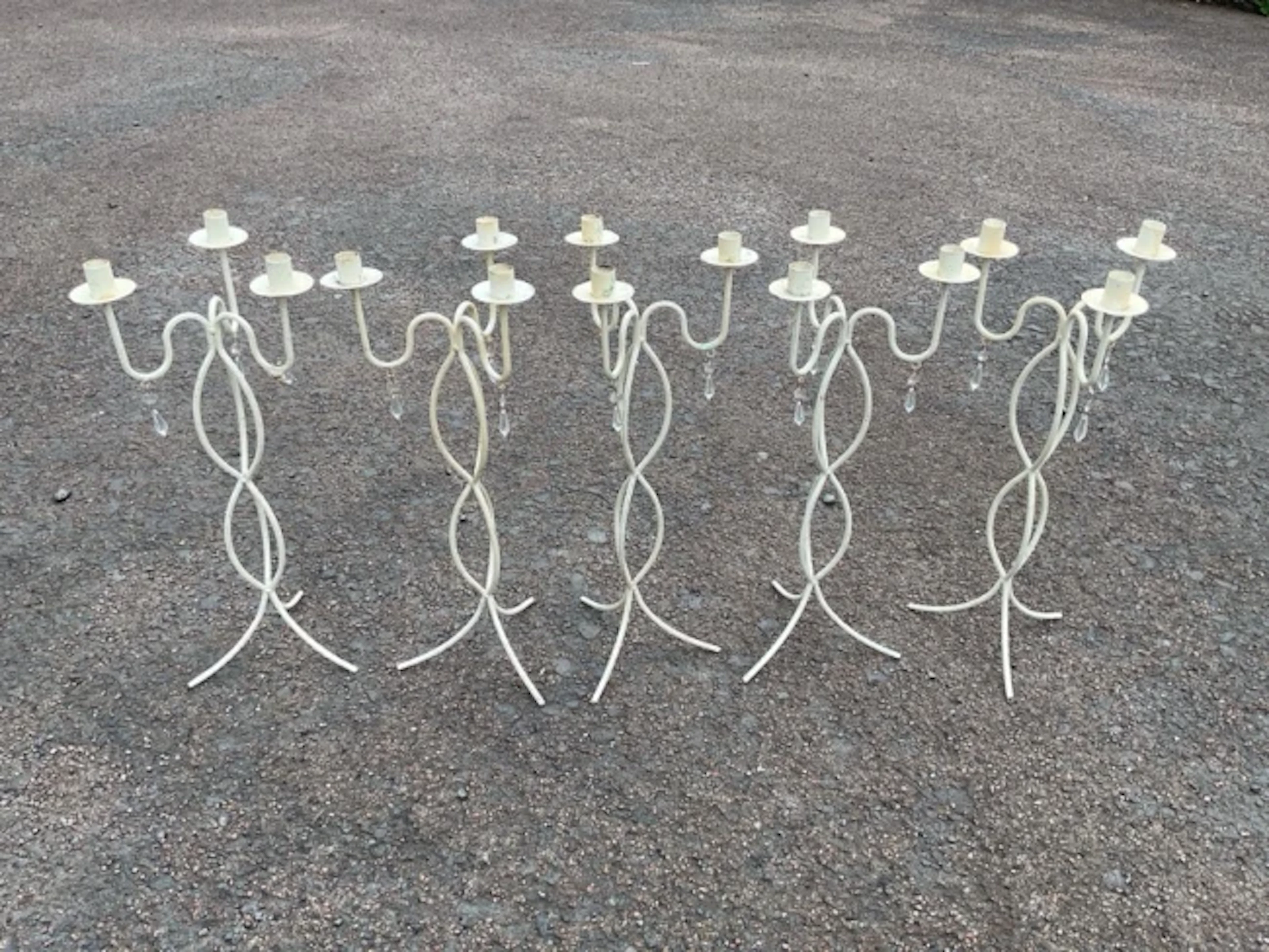 A set of five painted wrought iron candelabra each with three candleholders