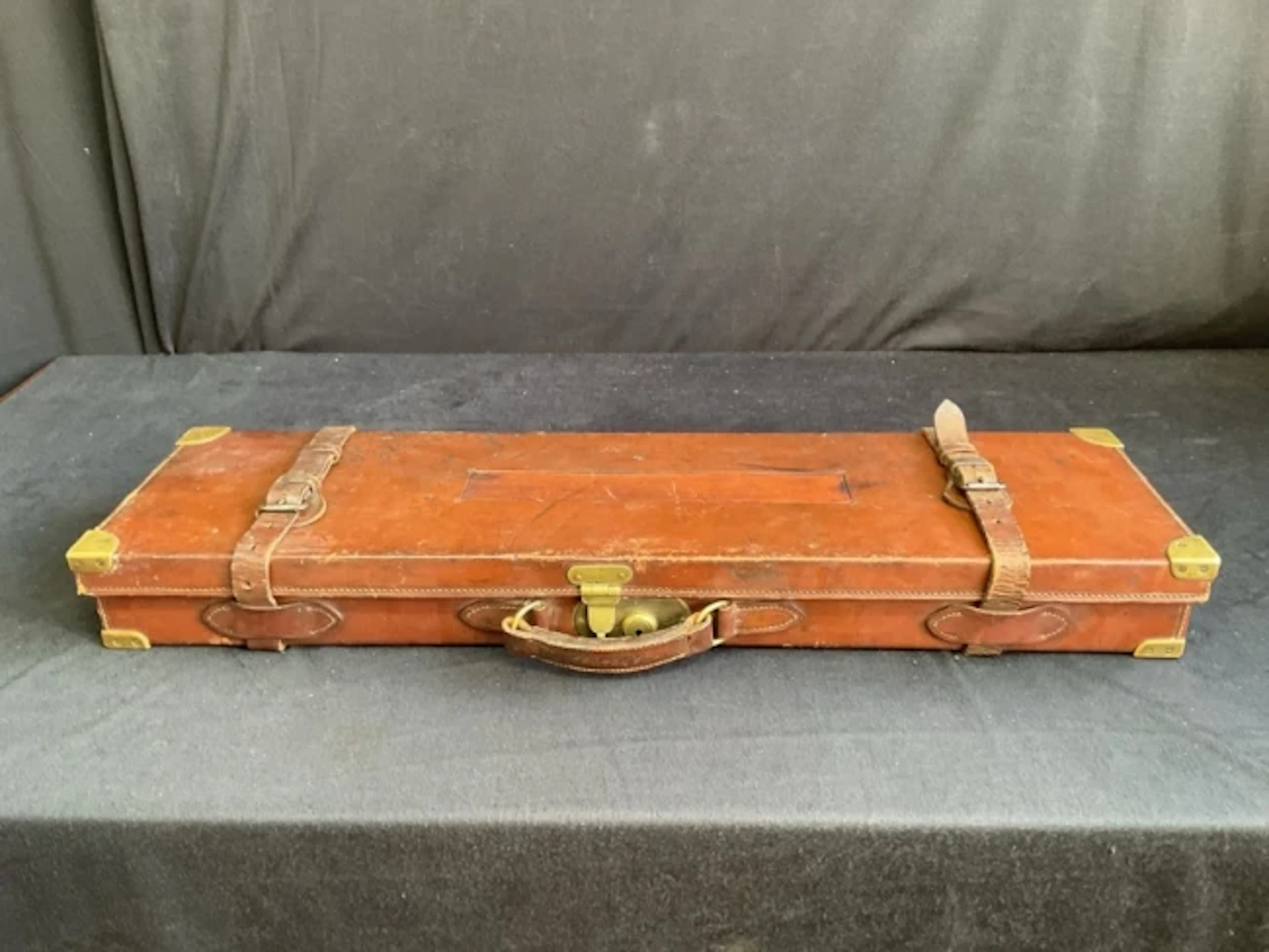A leather gun case with brass mounts having fitted interior containing