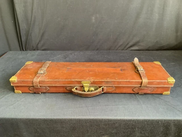 A leather gun case with brass mounts having fitted interior containing
