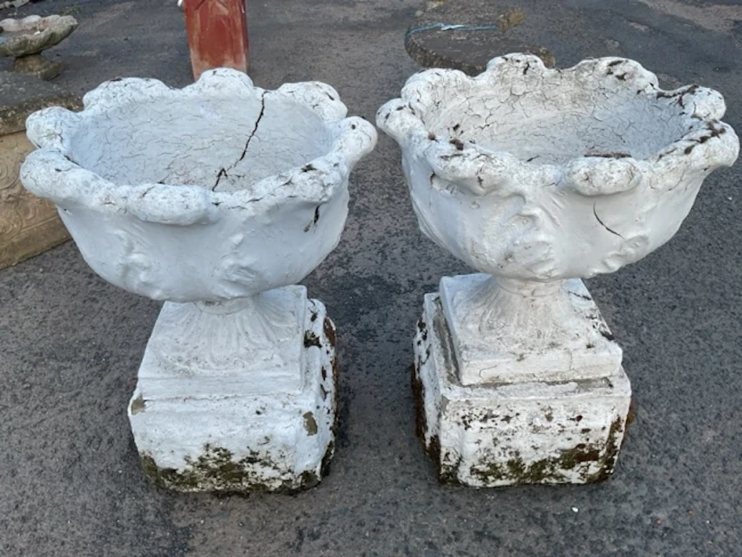 A pair of painted Victorian garden urns on stands, with leaf cast