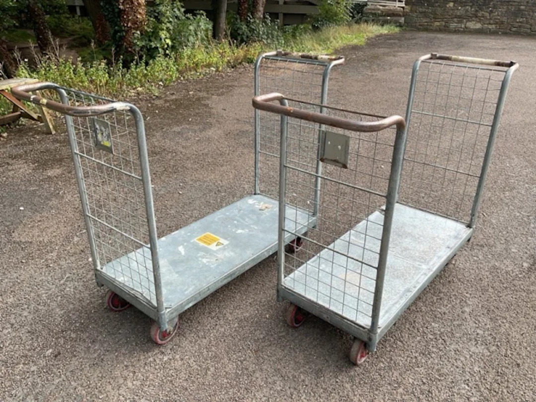 A pair of rectangular galvanised trolleys with handles to ends above