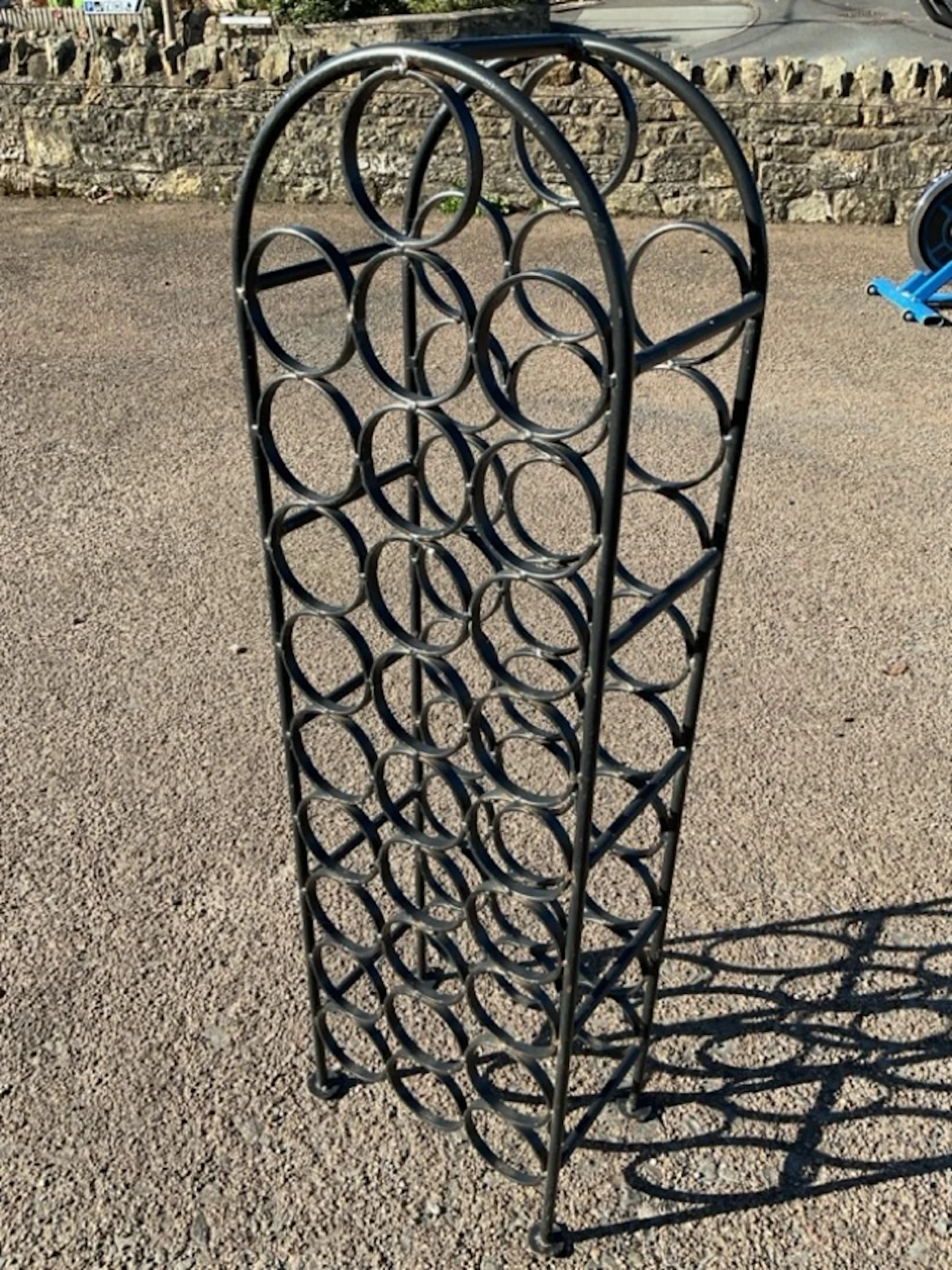 A metal wine rack, the arched frame to take twenty eight bottles. (43in)