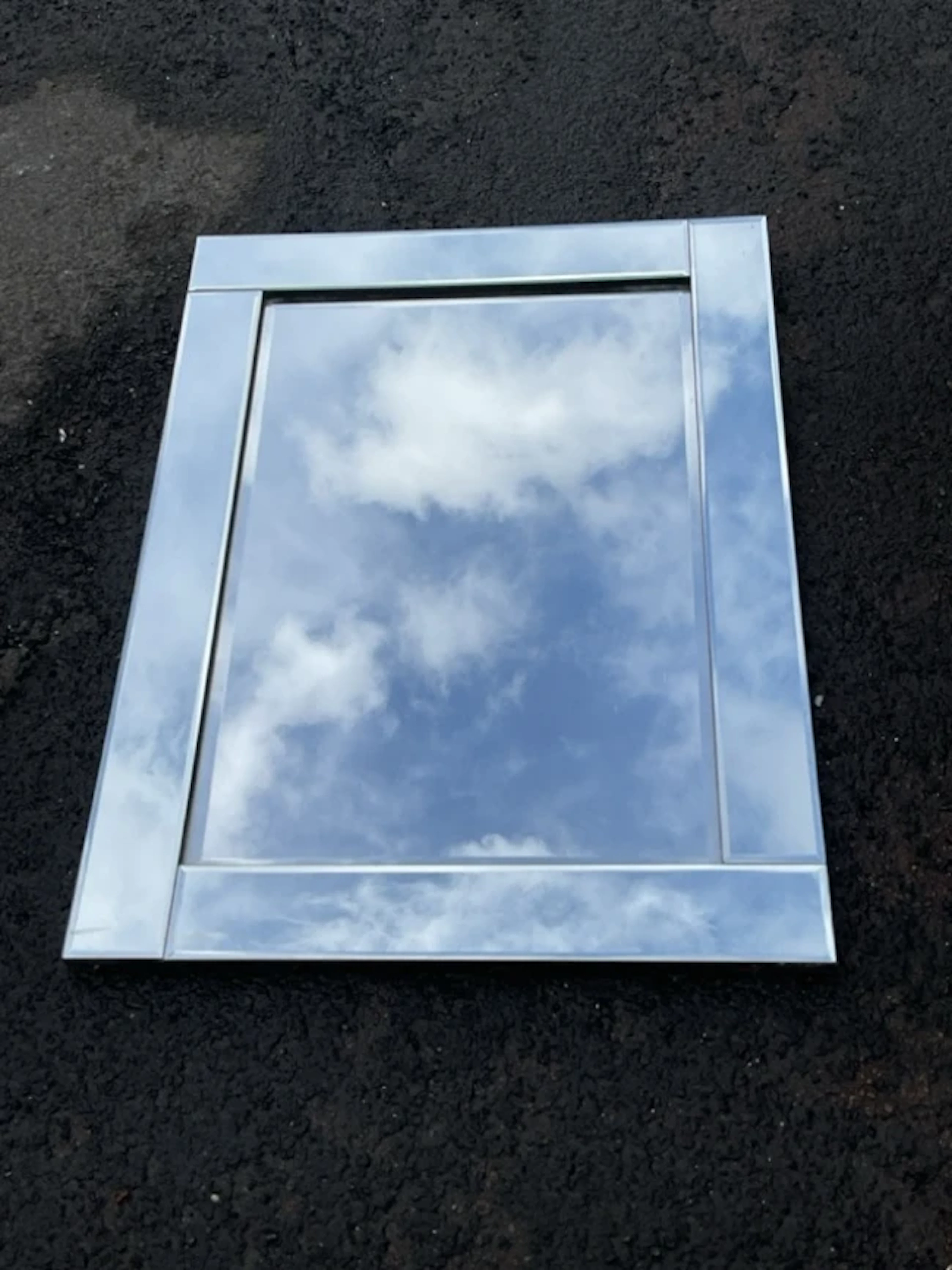 A contemporary mirror with five bevel cut plates having raised border.