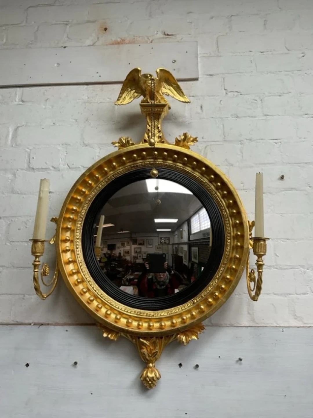A regency carved gilt pine convex girandole mirror with eagle finial