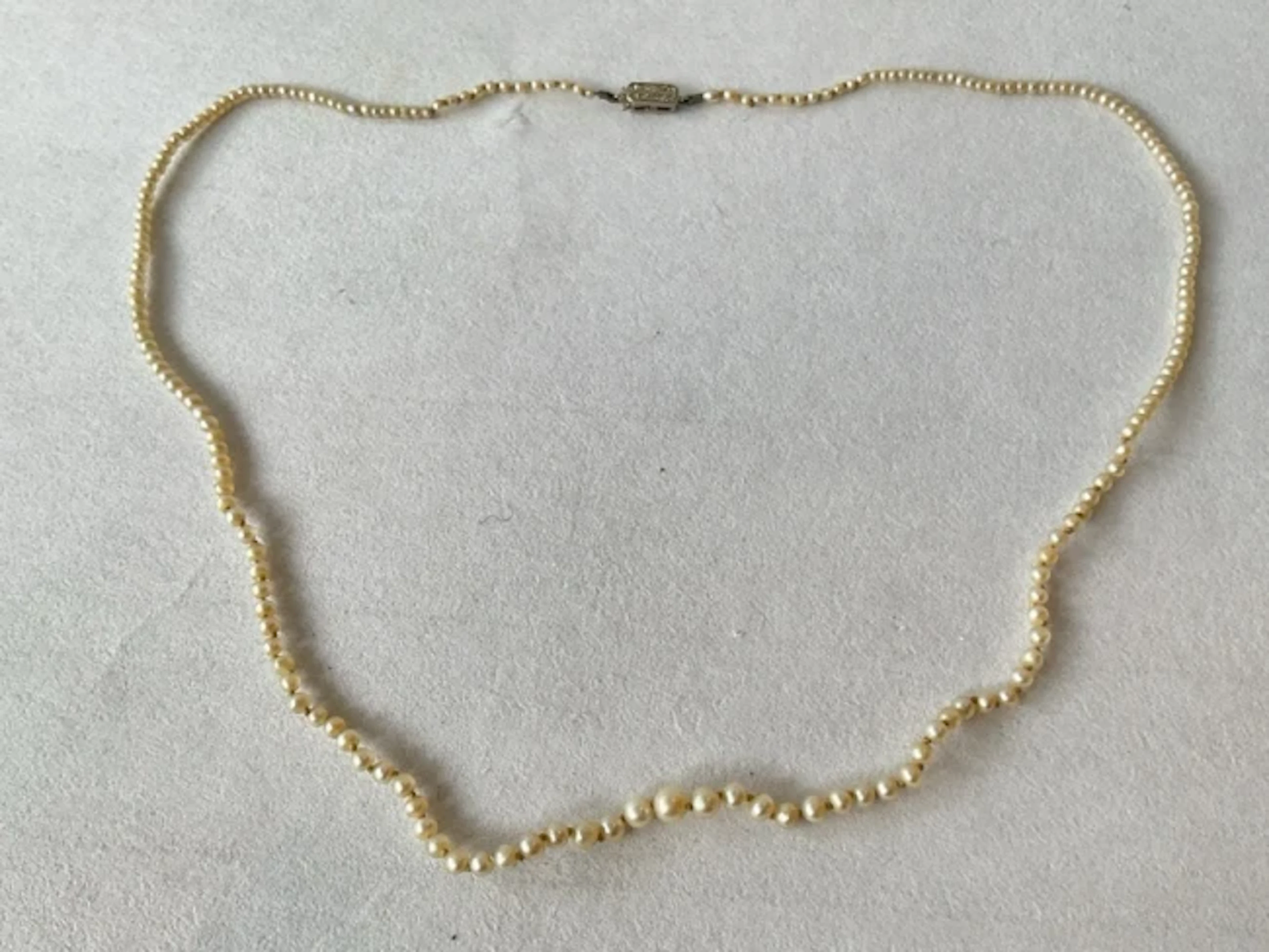 An antique partly hand-knotted string of graduated pearls, having