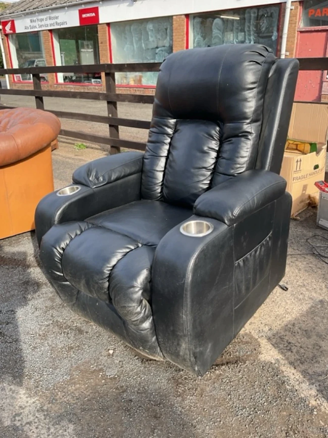 A black vinyl upholstered recliner armchair with deeply padded rectangular