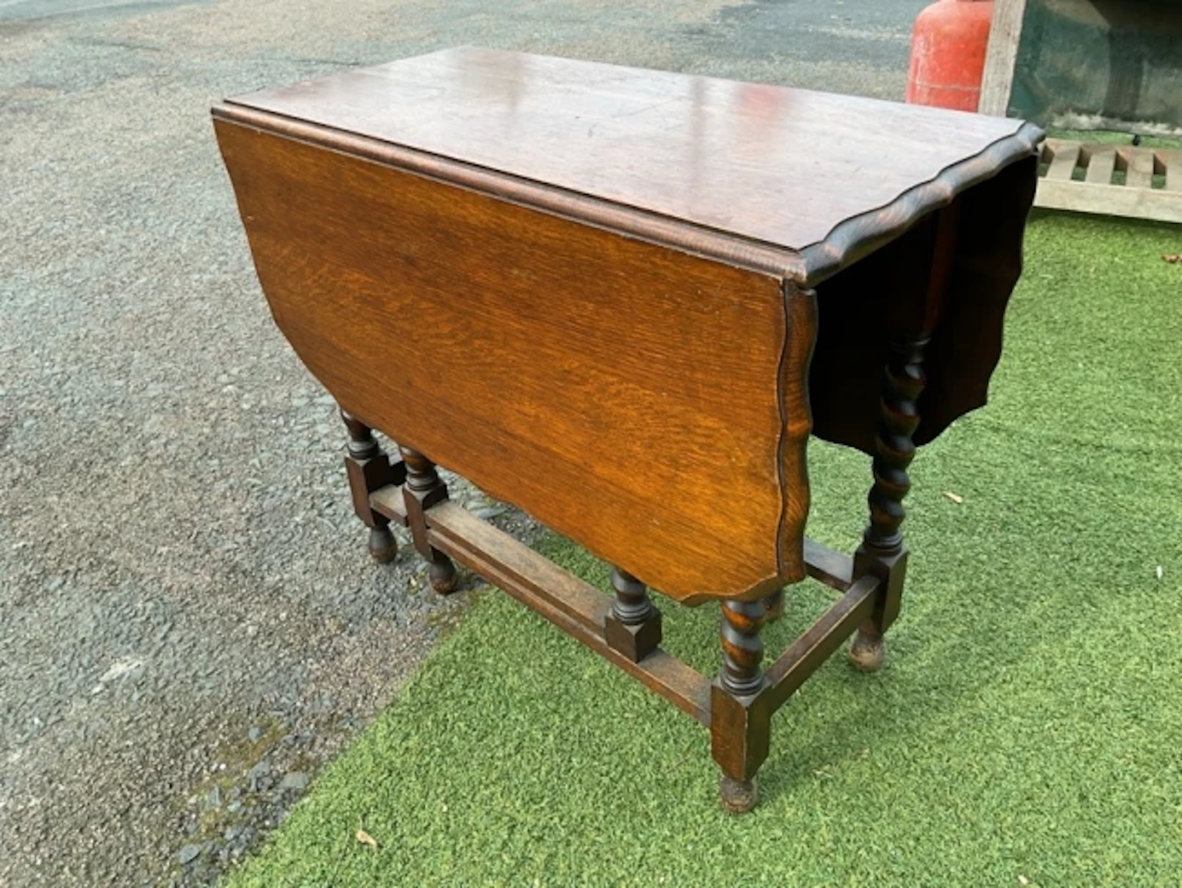 An oak dining table with scalloped rectangular top having two drop-leaves