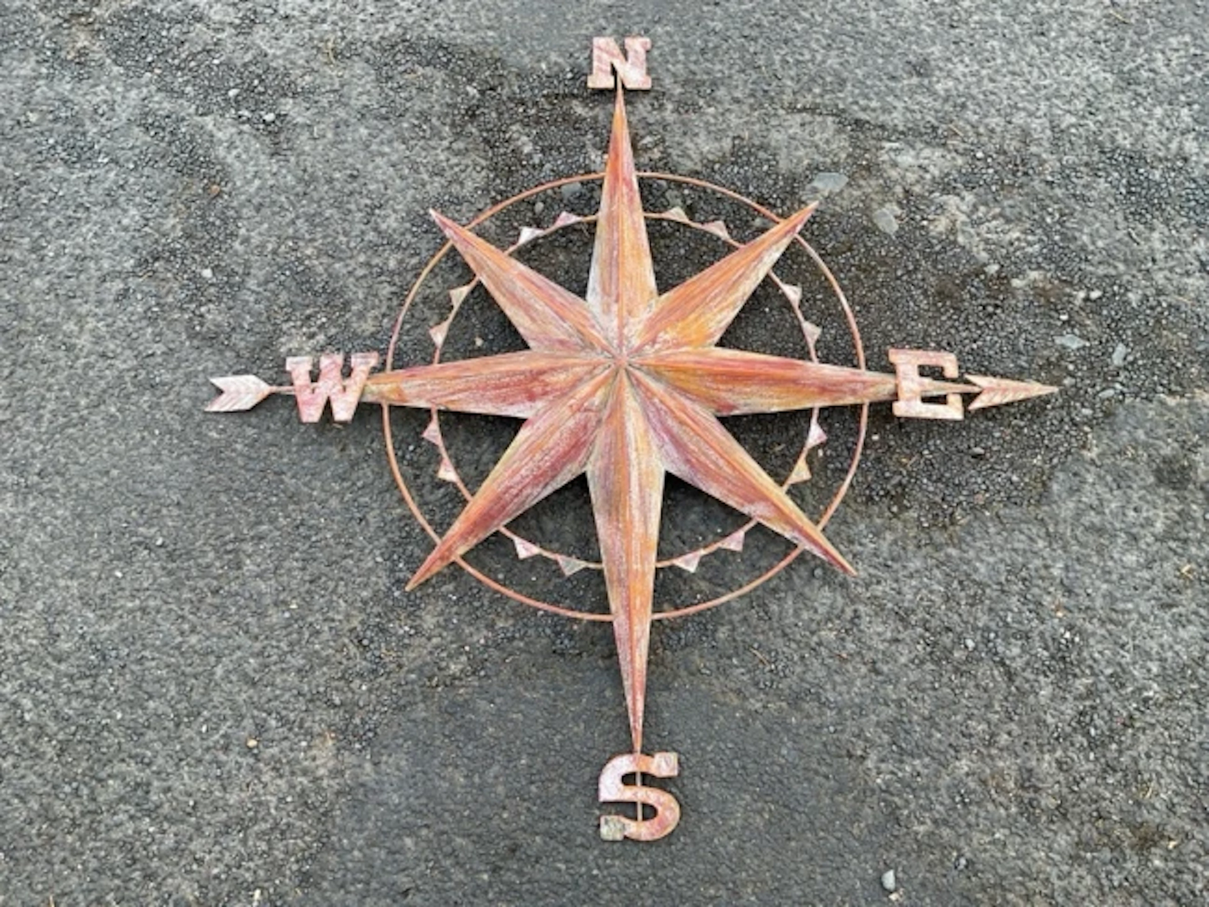 A wall-hanging painted metal compass point panel with central star