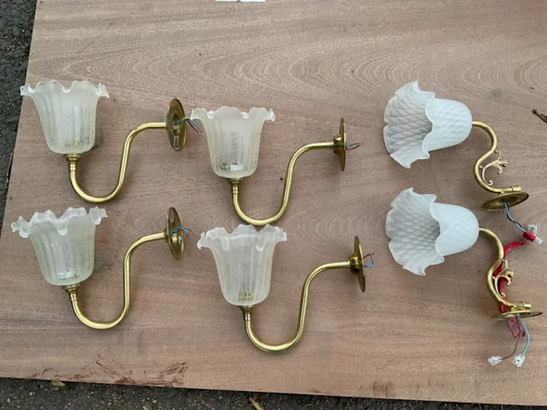 A set of four wall lights with circular brass wallplates and shaped