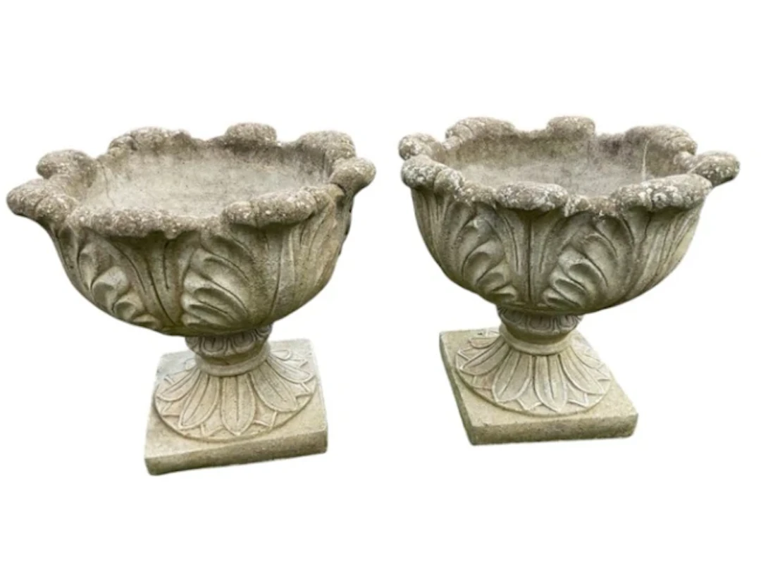 A pair of composition stone garden urns with leaf moulded bowls and