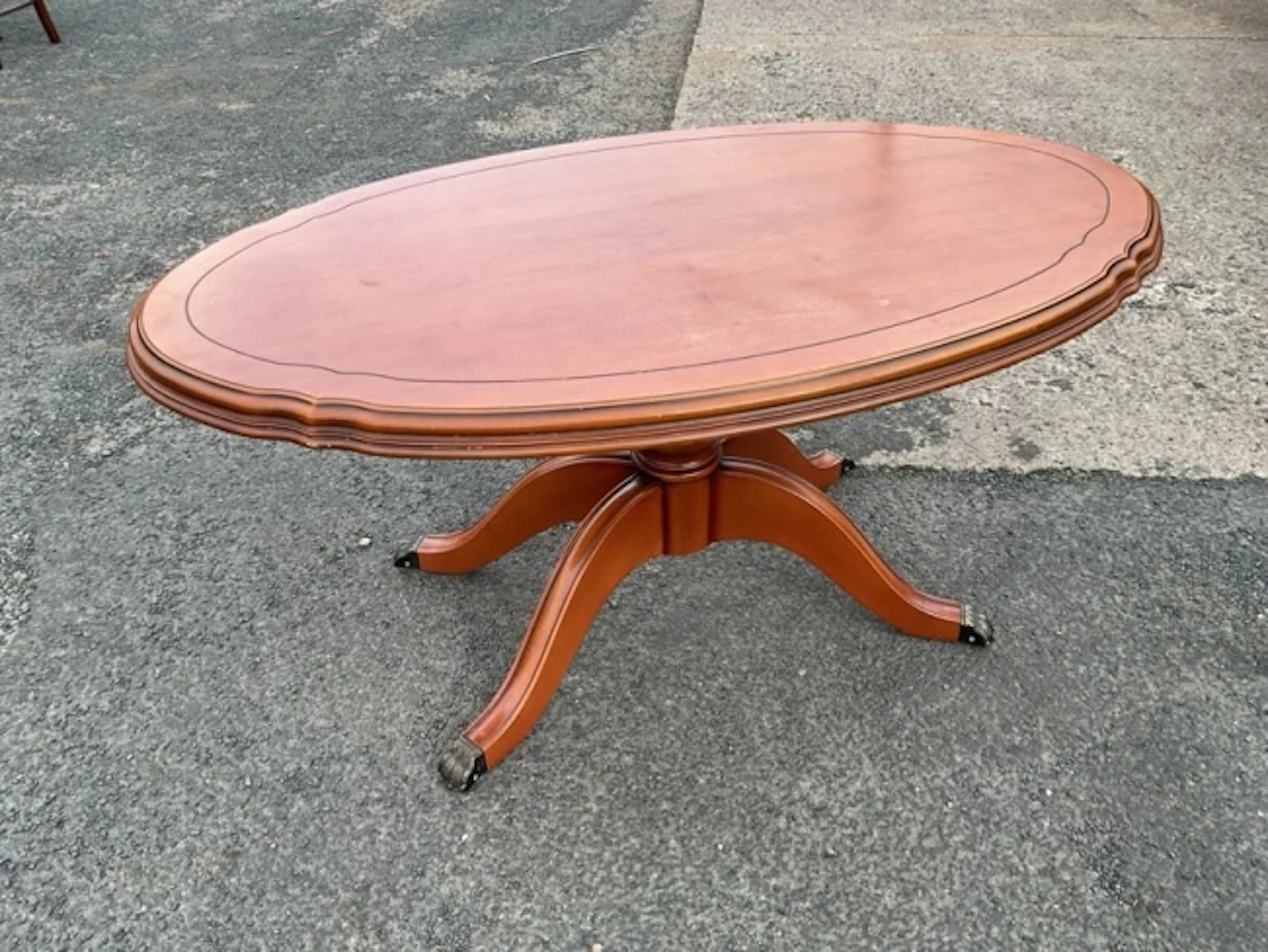 A regency style yew coffee table with oval moulded top on a turned