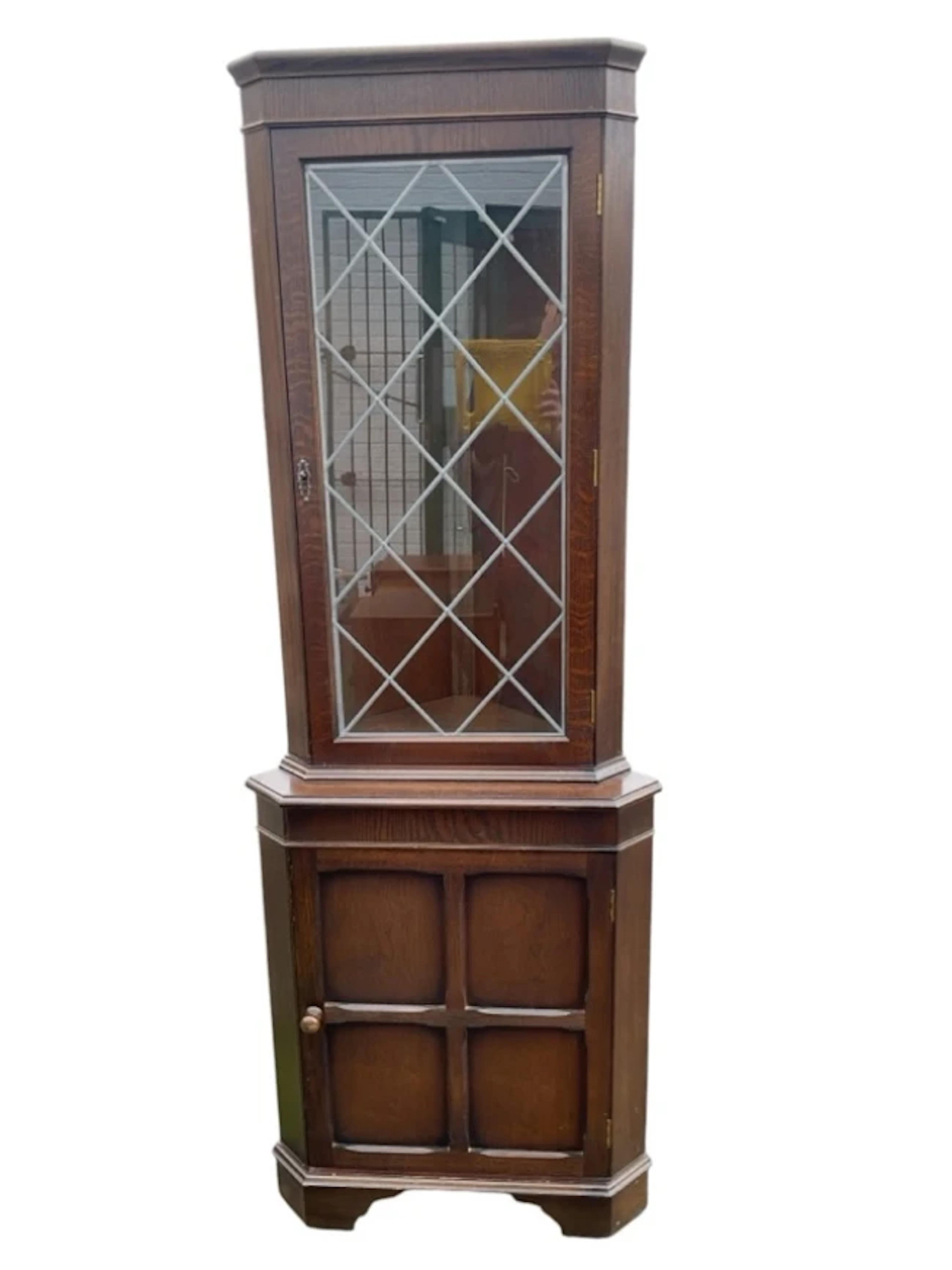 An oak corner cabinet with moulded cornice above a rectangular leaded