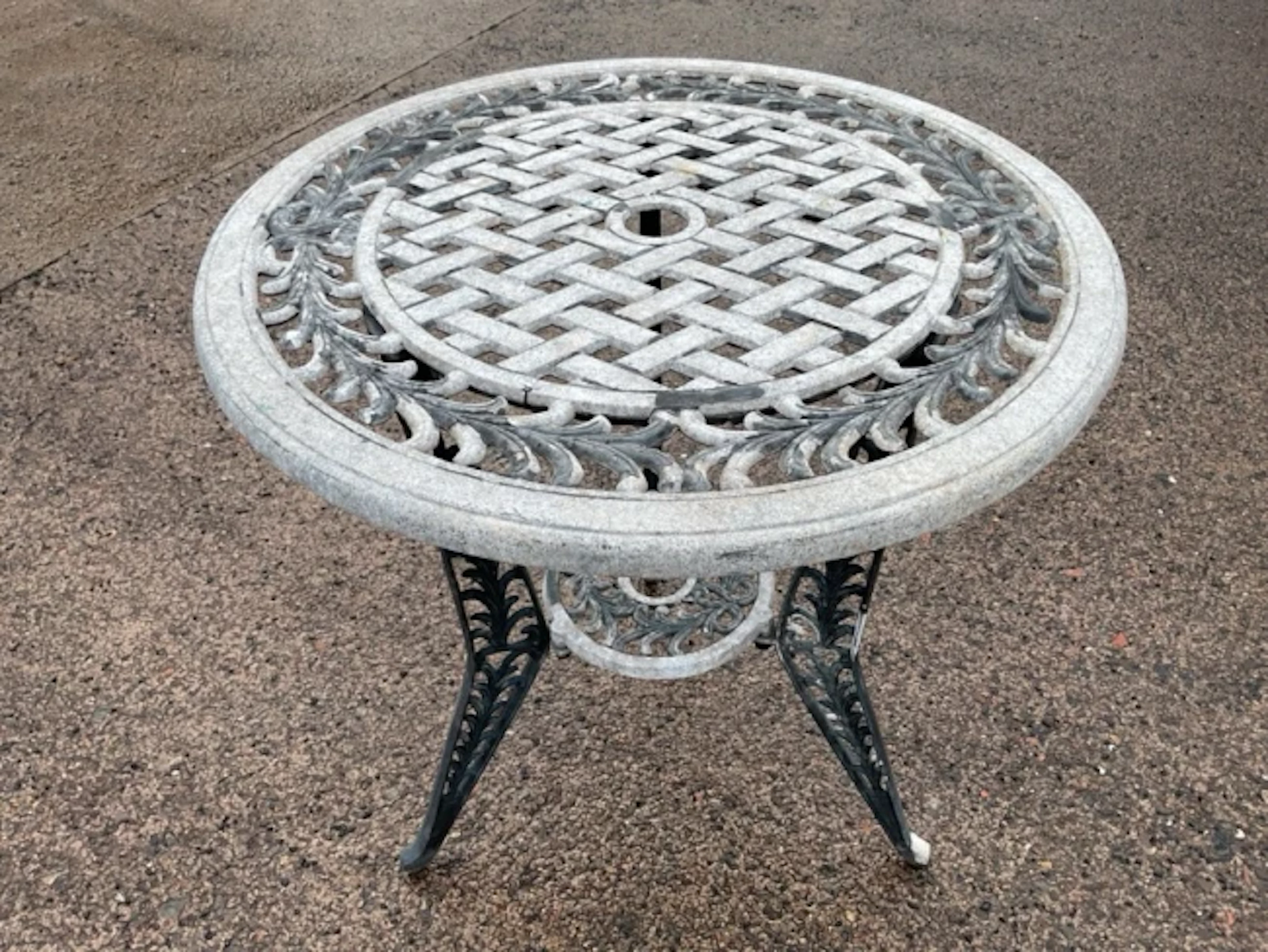 A circular metal garden table, the top with pierced latticework panel