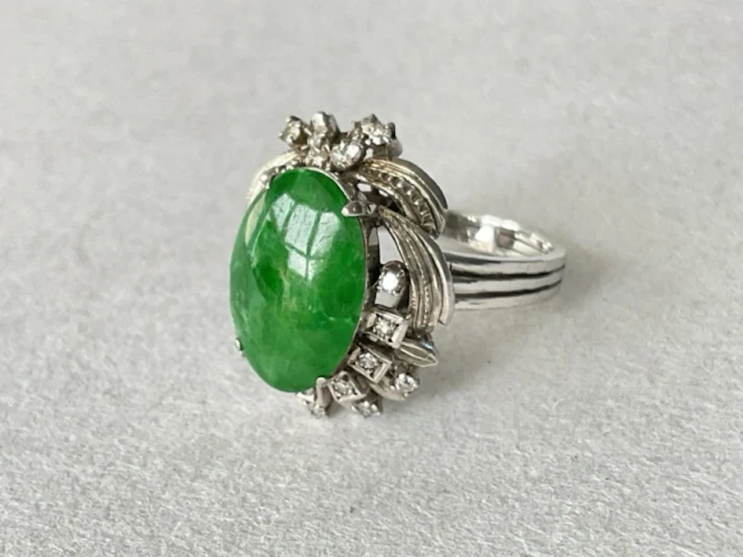 An 18ct white gold ring with central jade cabochon and 19 accent diamonds