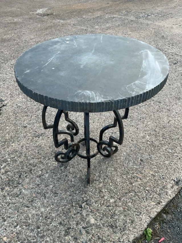 A garden table with wrought iron scrolled base having circular associated