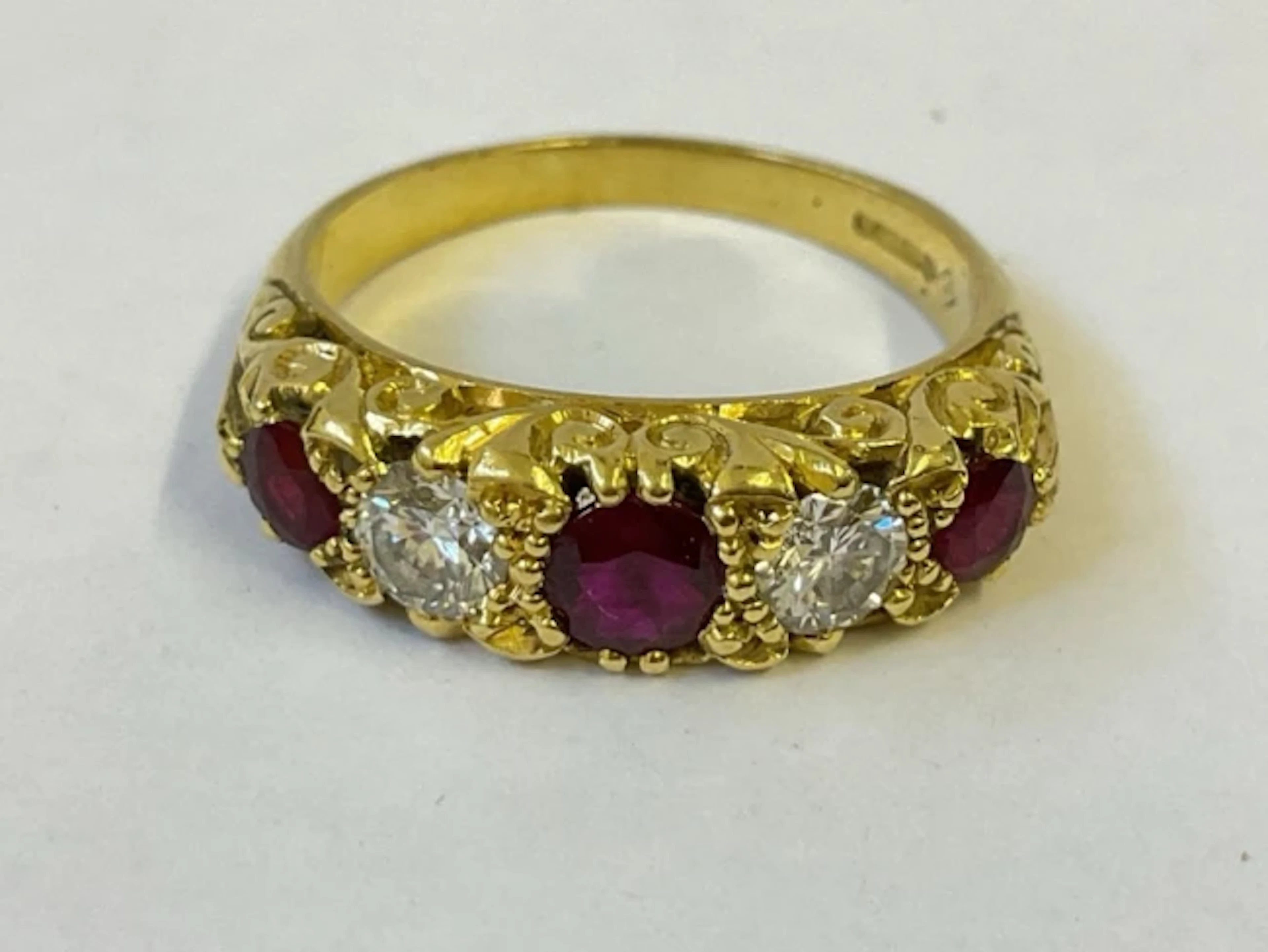An 18ct gold five stone ruby & diamond ring, raised on pierced scrolled