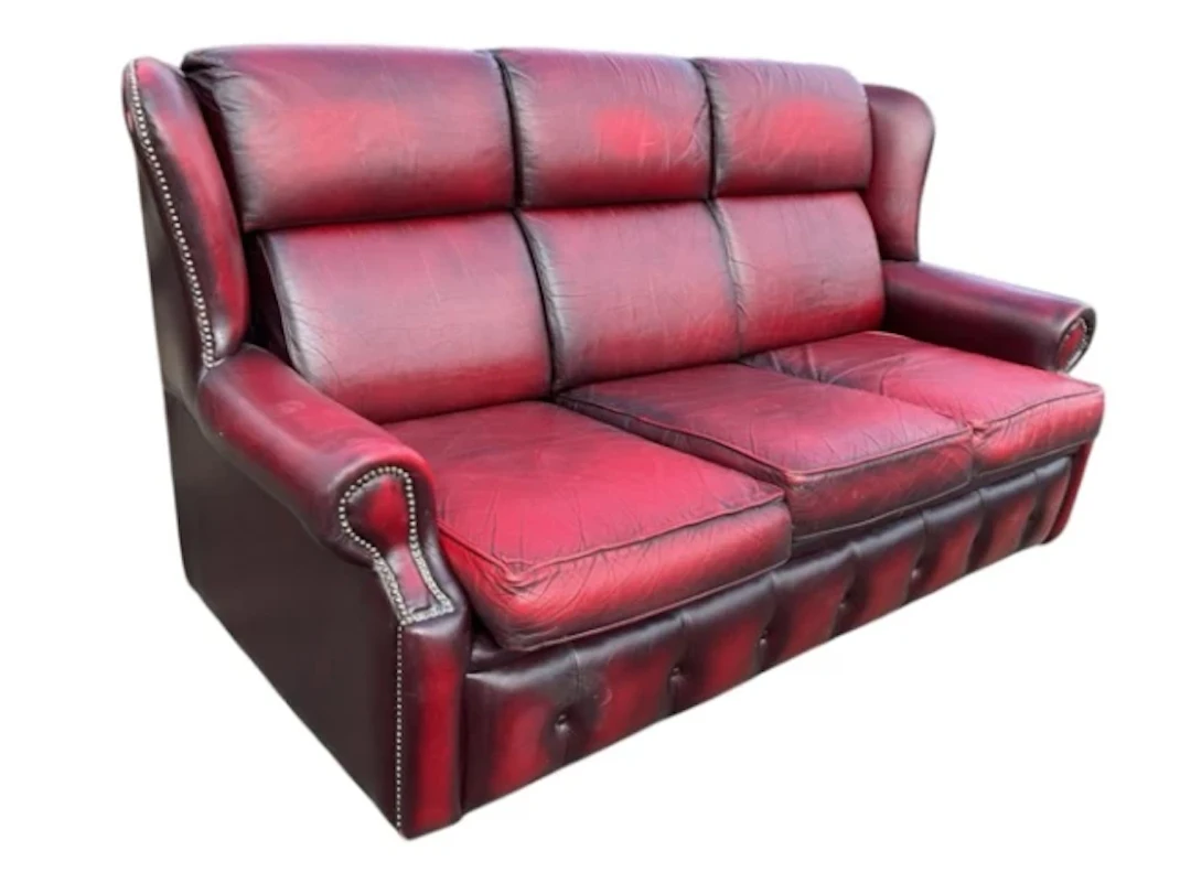A leather upholstered three-seater sofa with brass studding and loose
