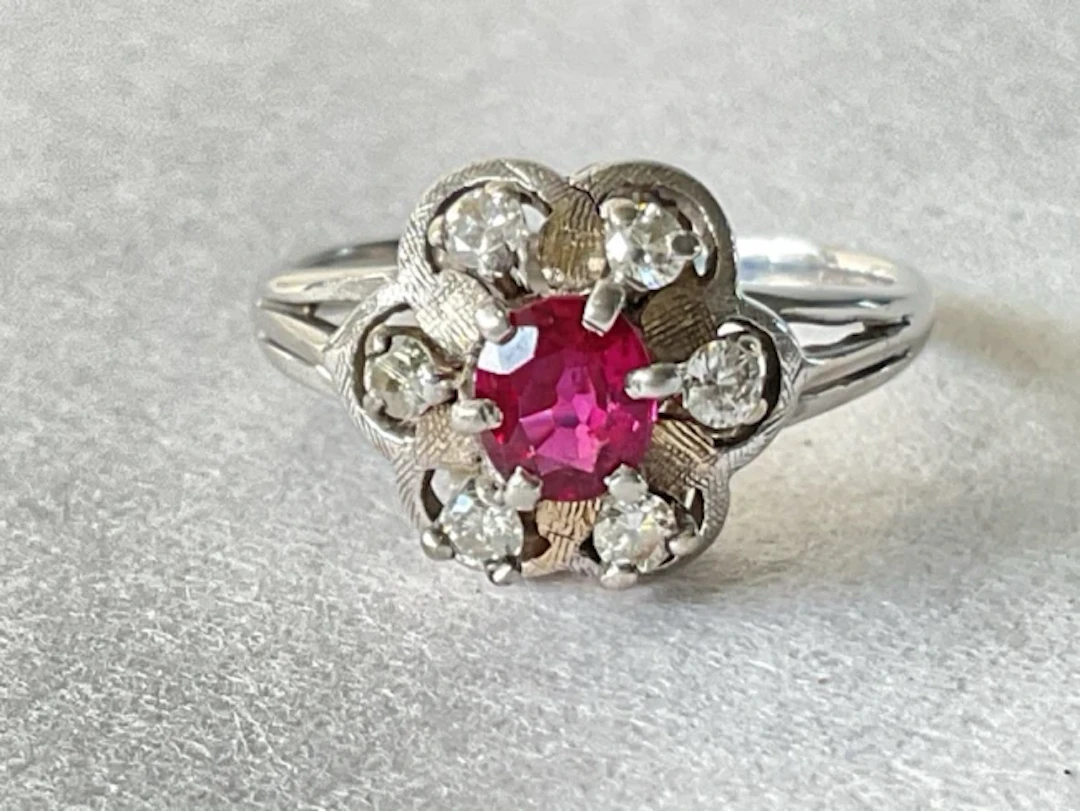 An 18ct white gold cluster ring with central claw set ruby surrounded
