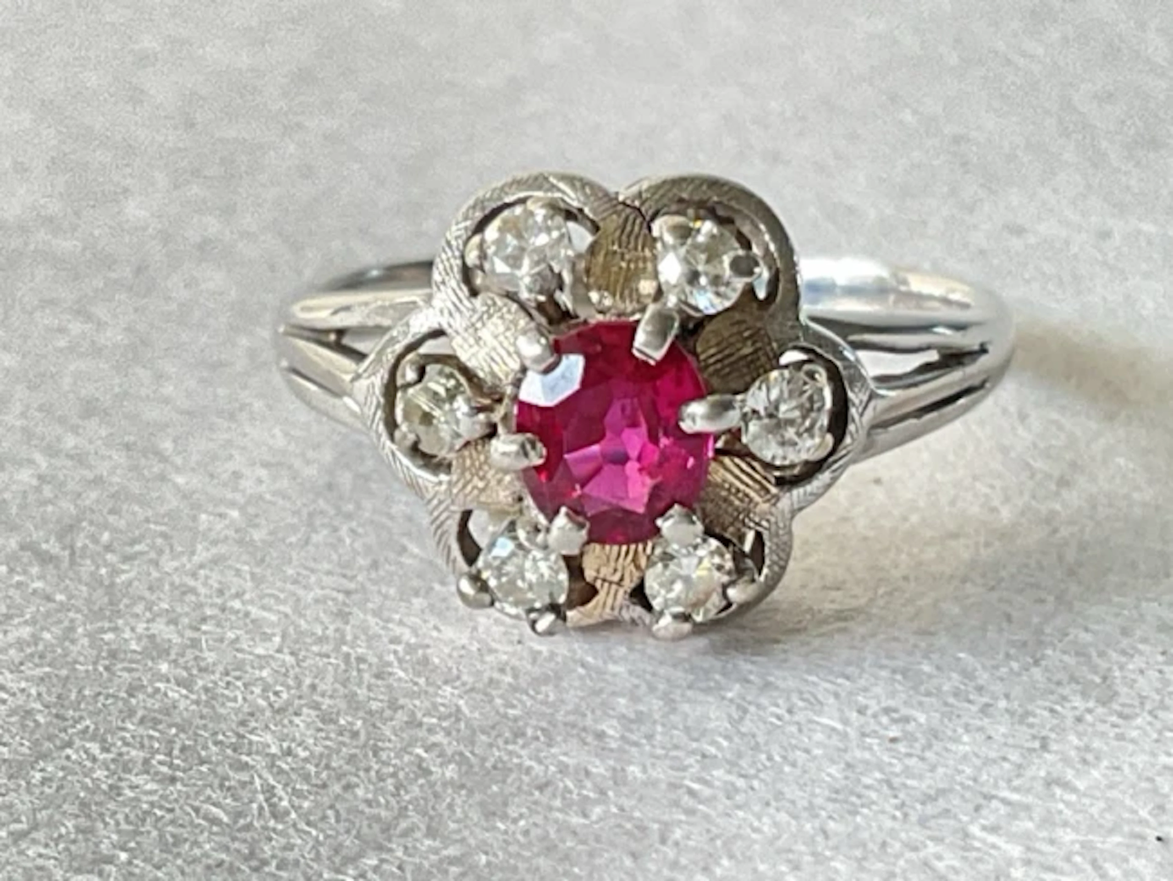An 18ct white gold cluster ring with central claw set ruby surrounded