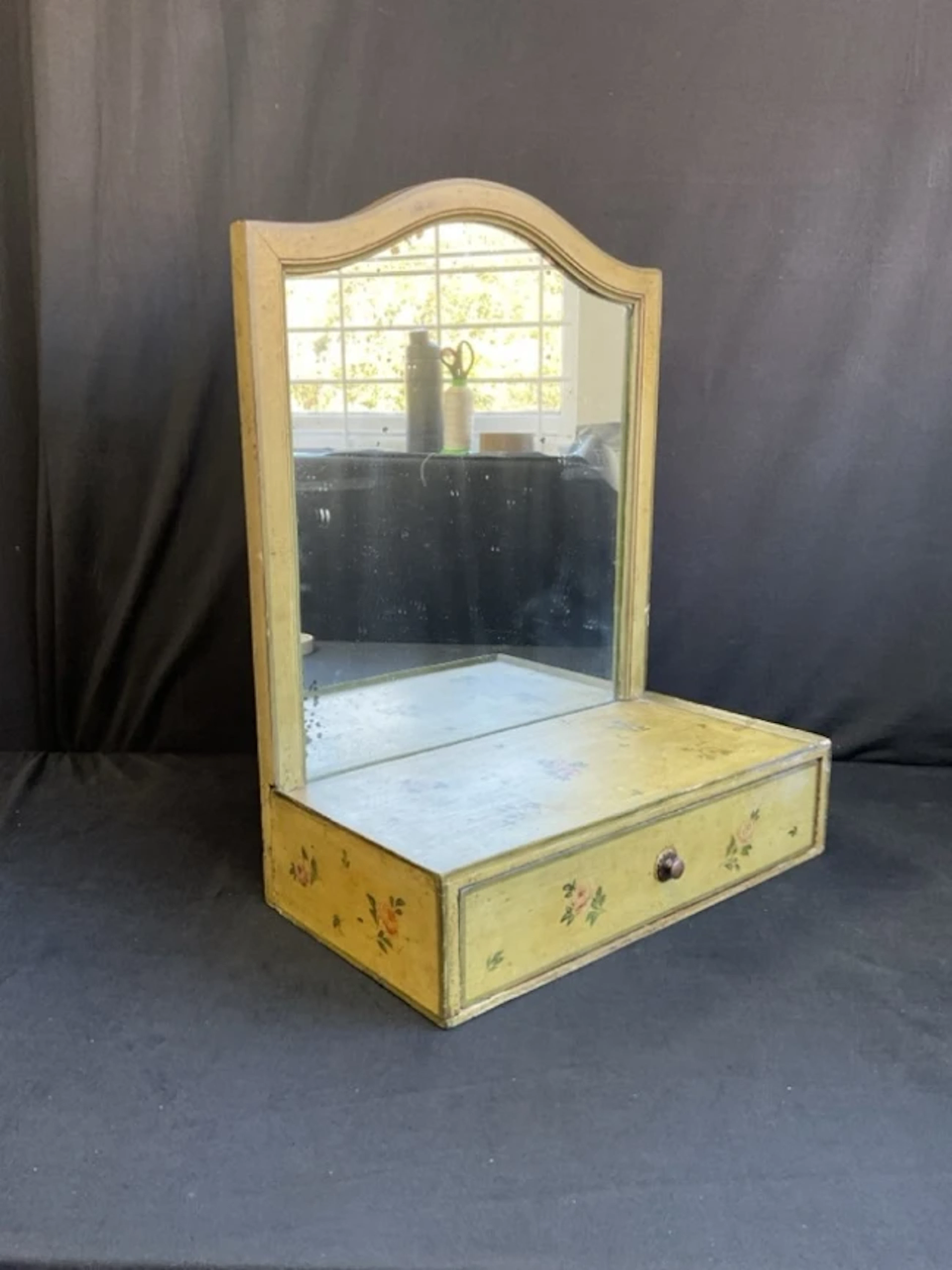 A painted dressing table mirror with arched frame above a rectangular