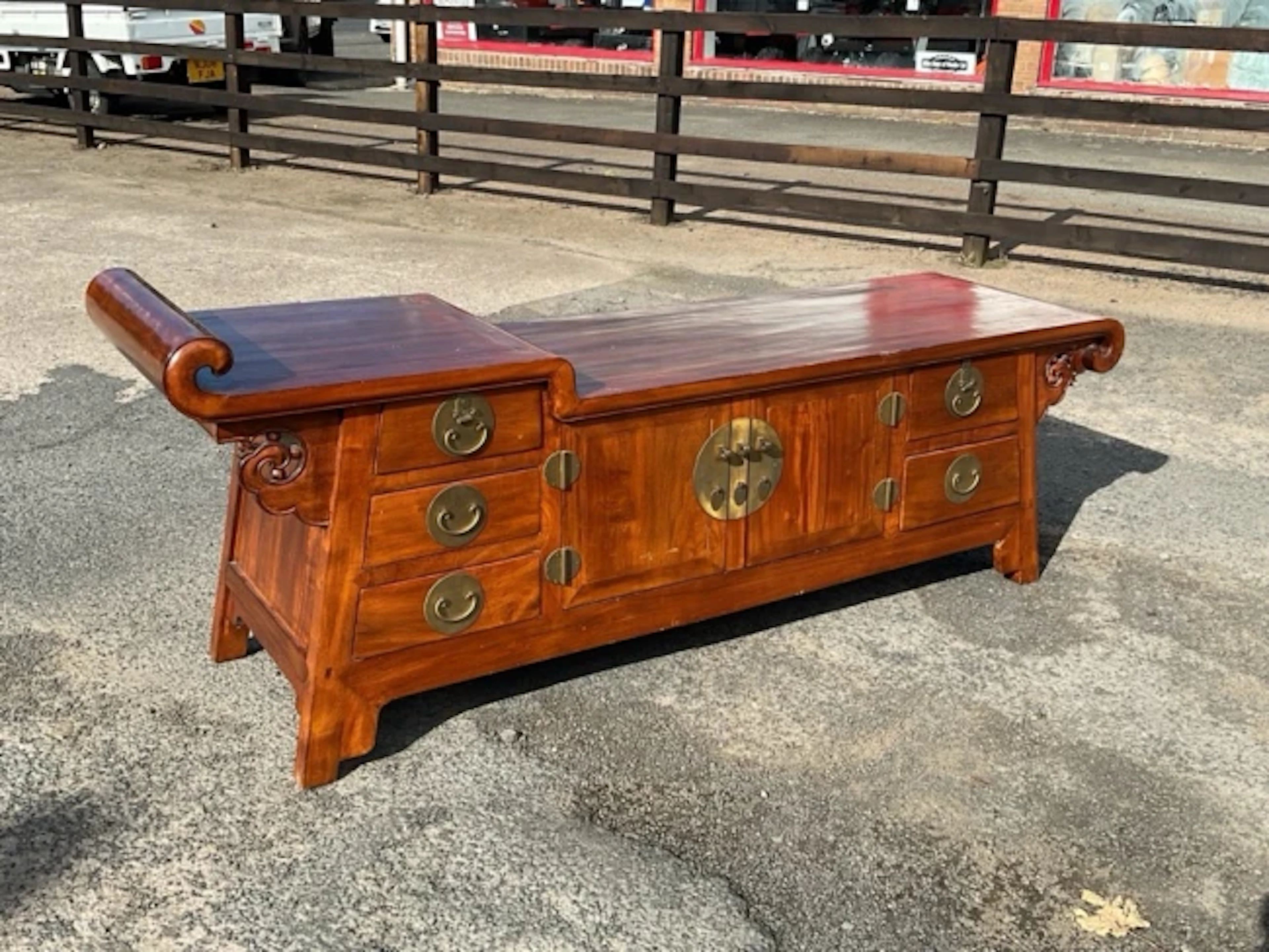 A Chinese side cabinet with raised section to scrolled panelled top