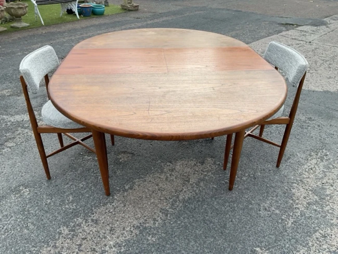 A circular teak G-plan dining table with integral folding extending