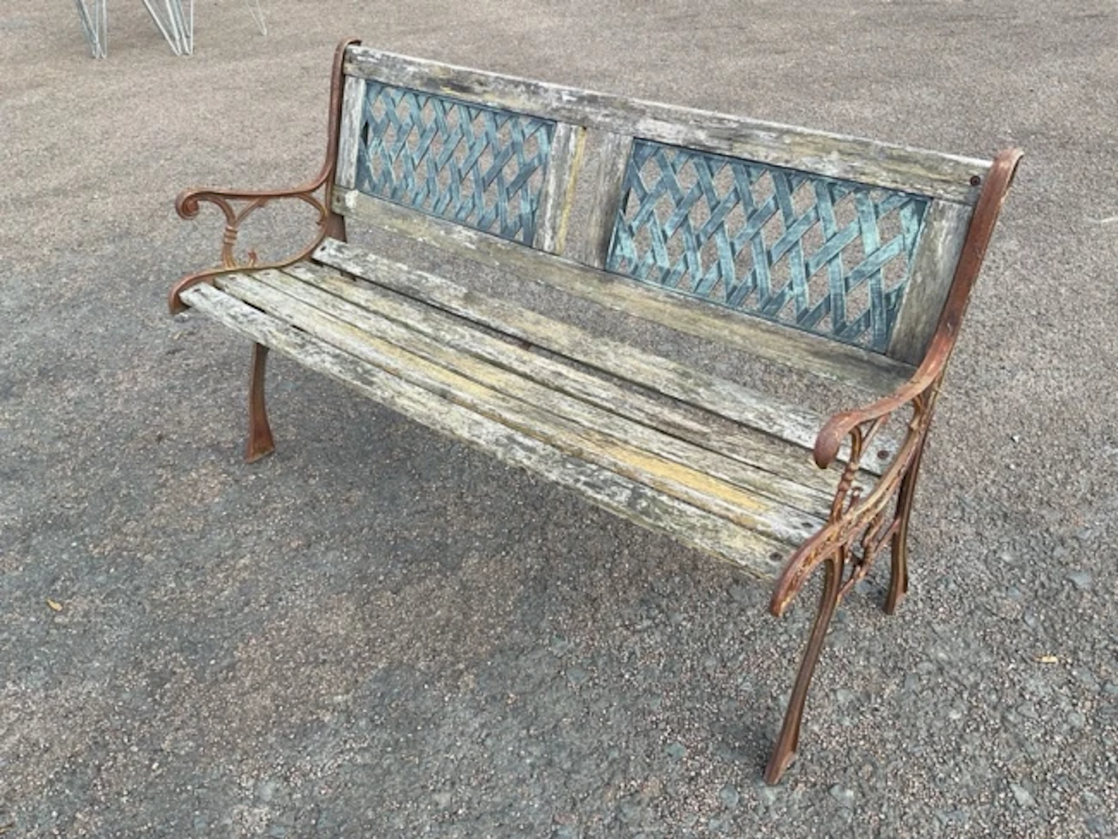 A wrought iron garden bench with resin latticework panels to back