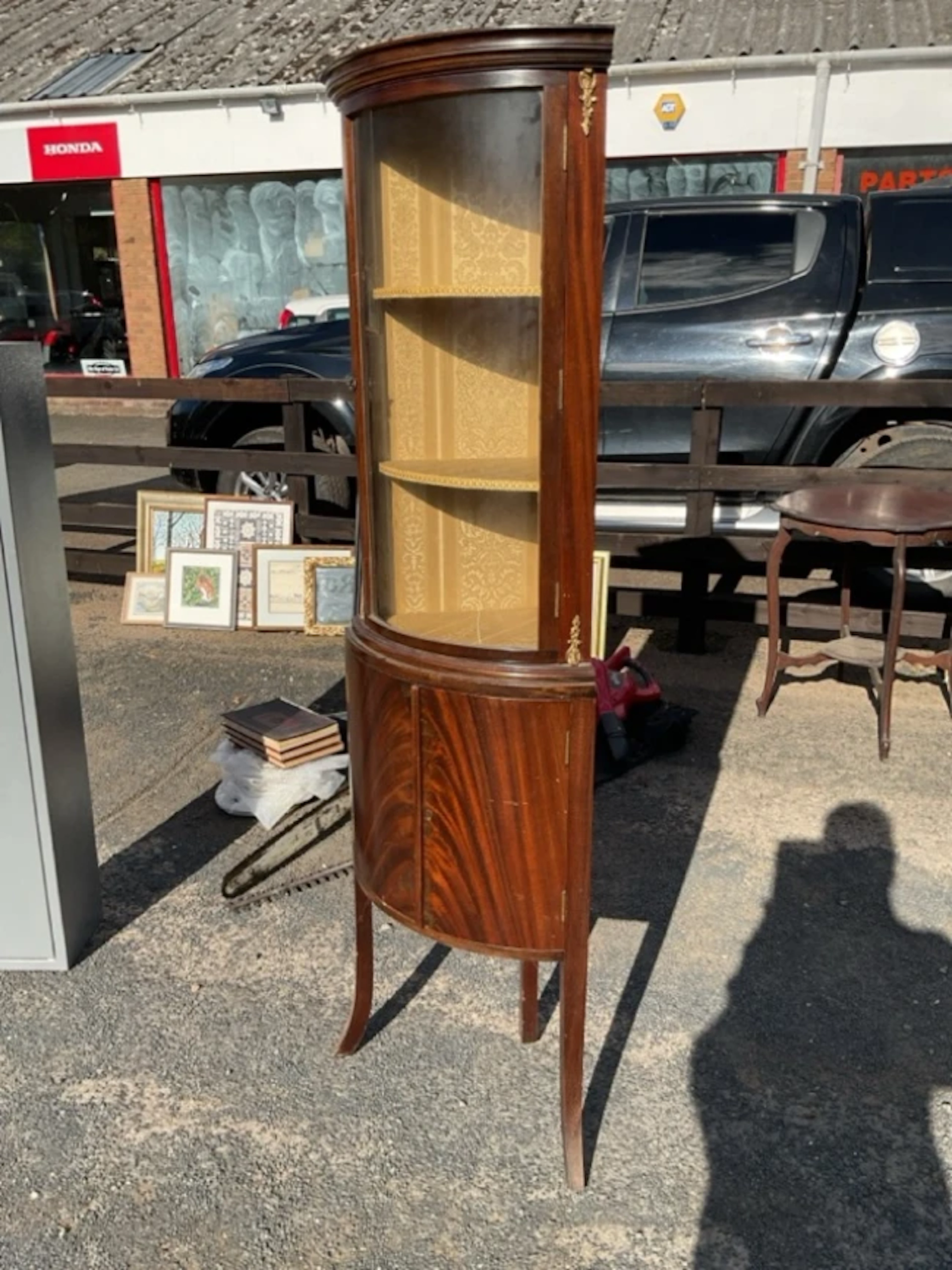 A bowfronted mahogany corner cabinet with gilt mounts having moulded