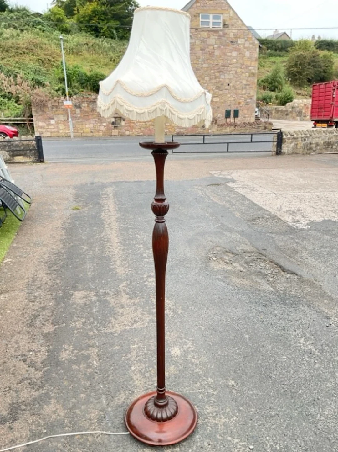 A mahogany standard lamp with tassled octagonal fabric shade on fluted