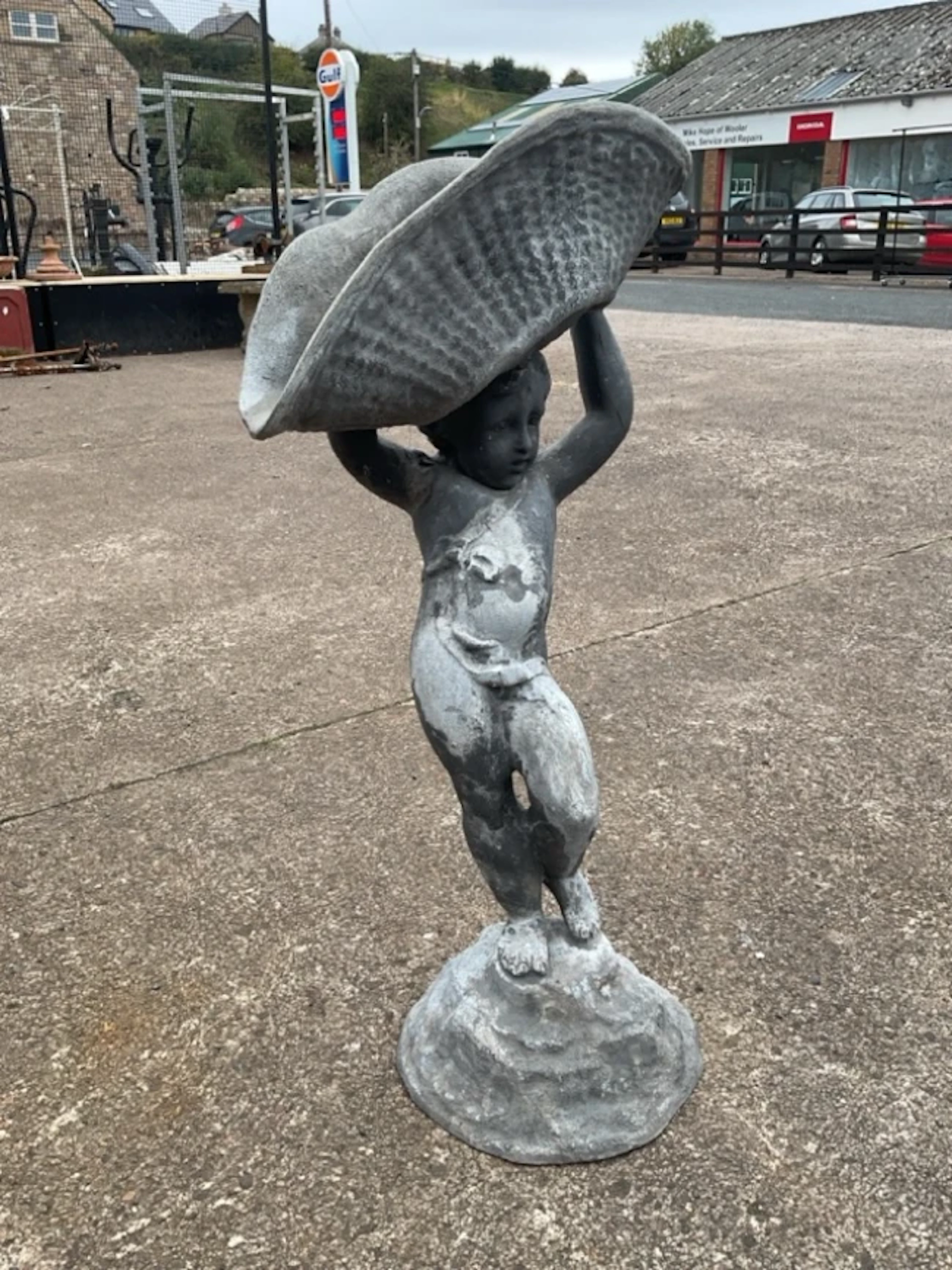 A nineteenth century lead putti supporting a ribbed basket, the figure